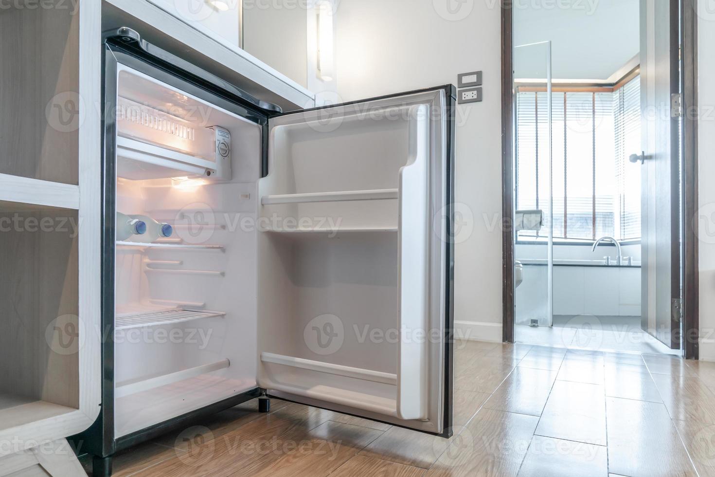 petit réfrigérateur ouvert sous le comptoir et devant les toilettes dans la chambre de luxe du complexe et de l'hôtel. photo