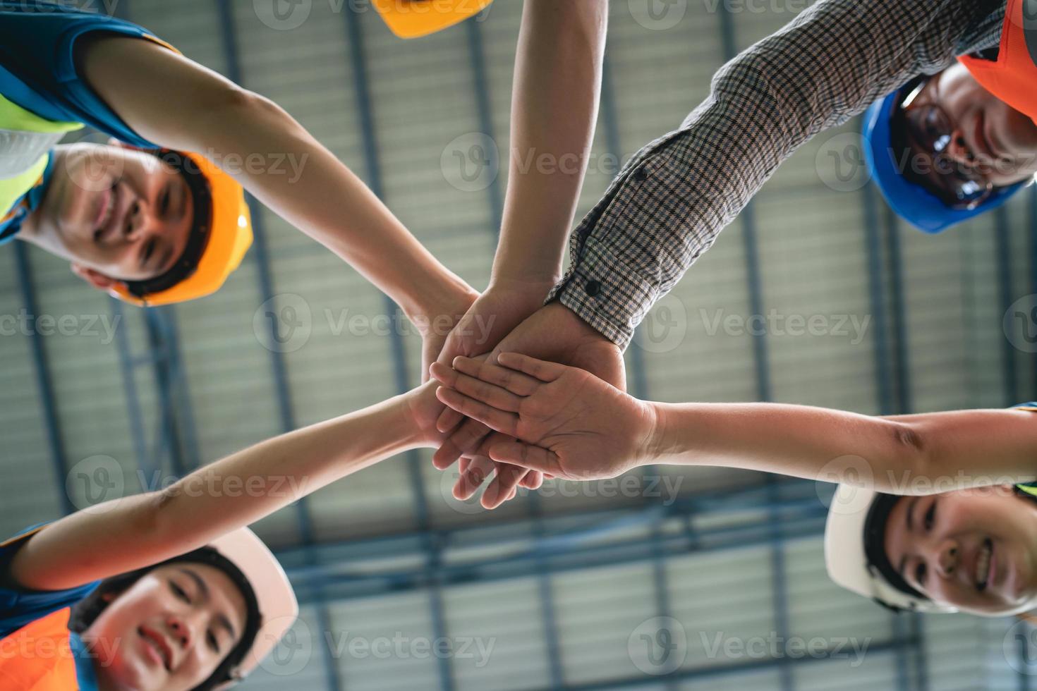 un groupe de travailleurs asiatiques dans un entrepôt industriel et une pile de main de suite de sécurité célèbrent un engagement réussi ou un accord. logistique, chaîne d'approvisionnement et entrepôt.unité de travail d'équipe sous le concept de vue. photo