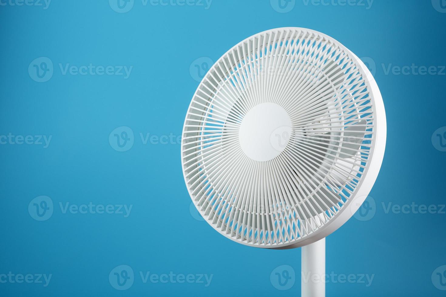 ventilateur électrique moderne blanc pour refroidir la pièce sur fond bleu. photo