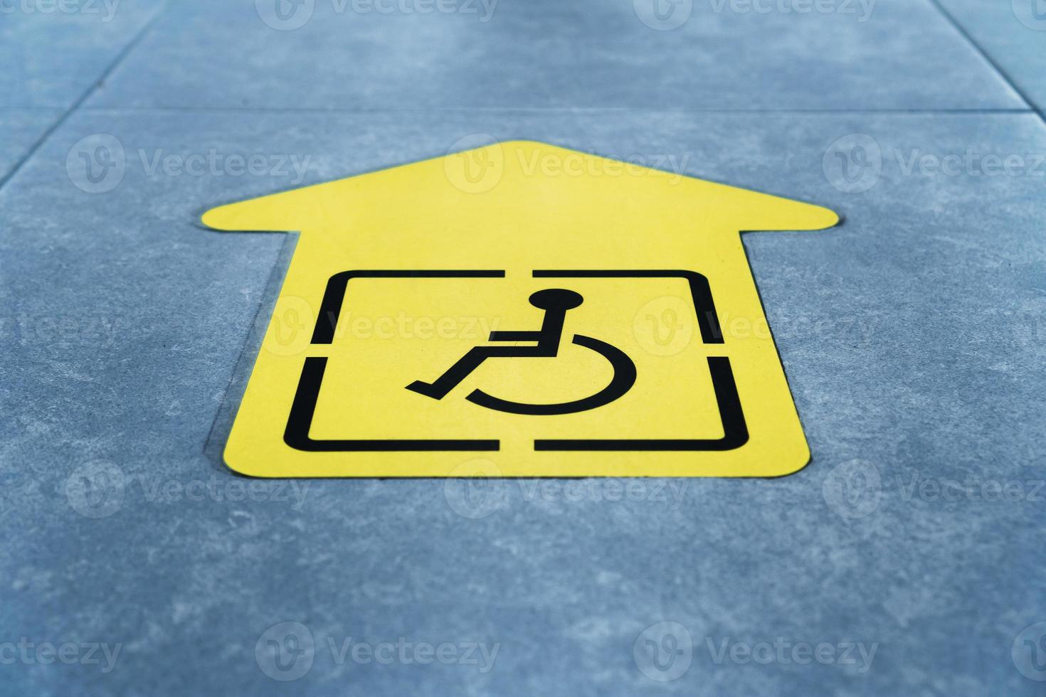 un dessin d'un fauteuil roulant sur une flèche jaune collée sur le carrelage de la salle d'attente photo