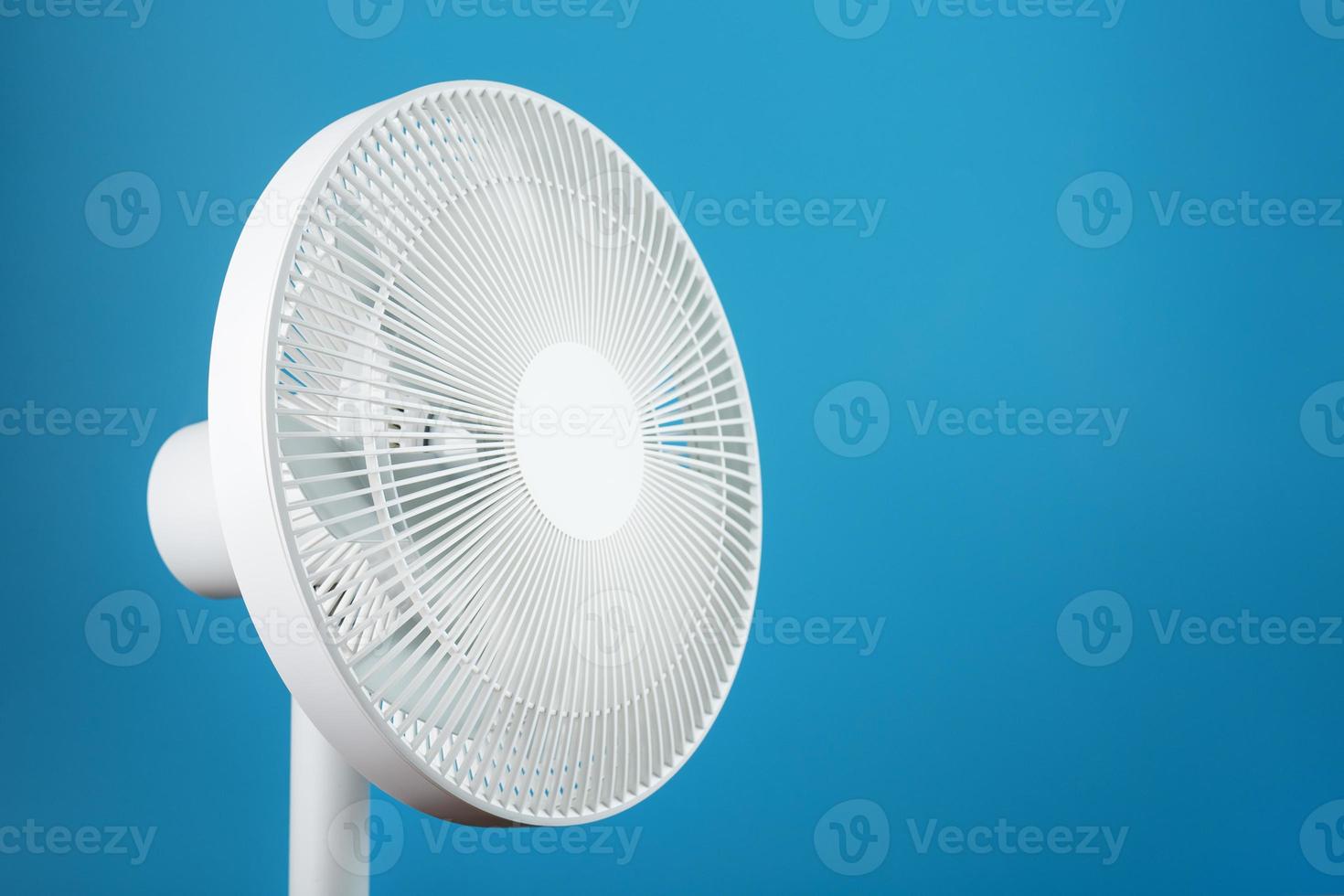 ventilateur électrique moderne blanc pour refroidir la pièce sur fond bleu. photo