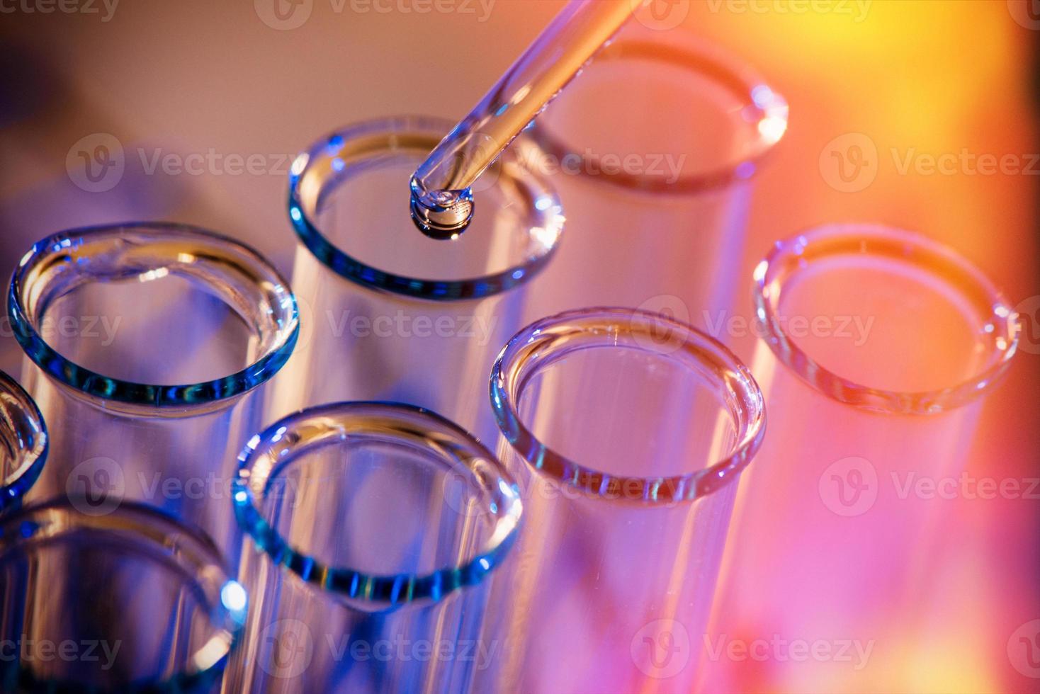 rangée de tubes à essai. concept de laboratoire médical ou scientifique, gouttelette liquide avec compte-gouttes sur fond bleu rouge, gros plan, photo macro.