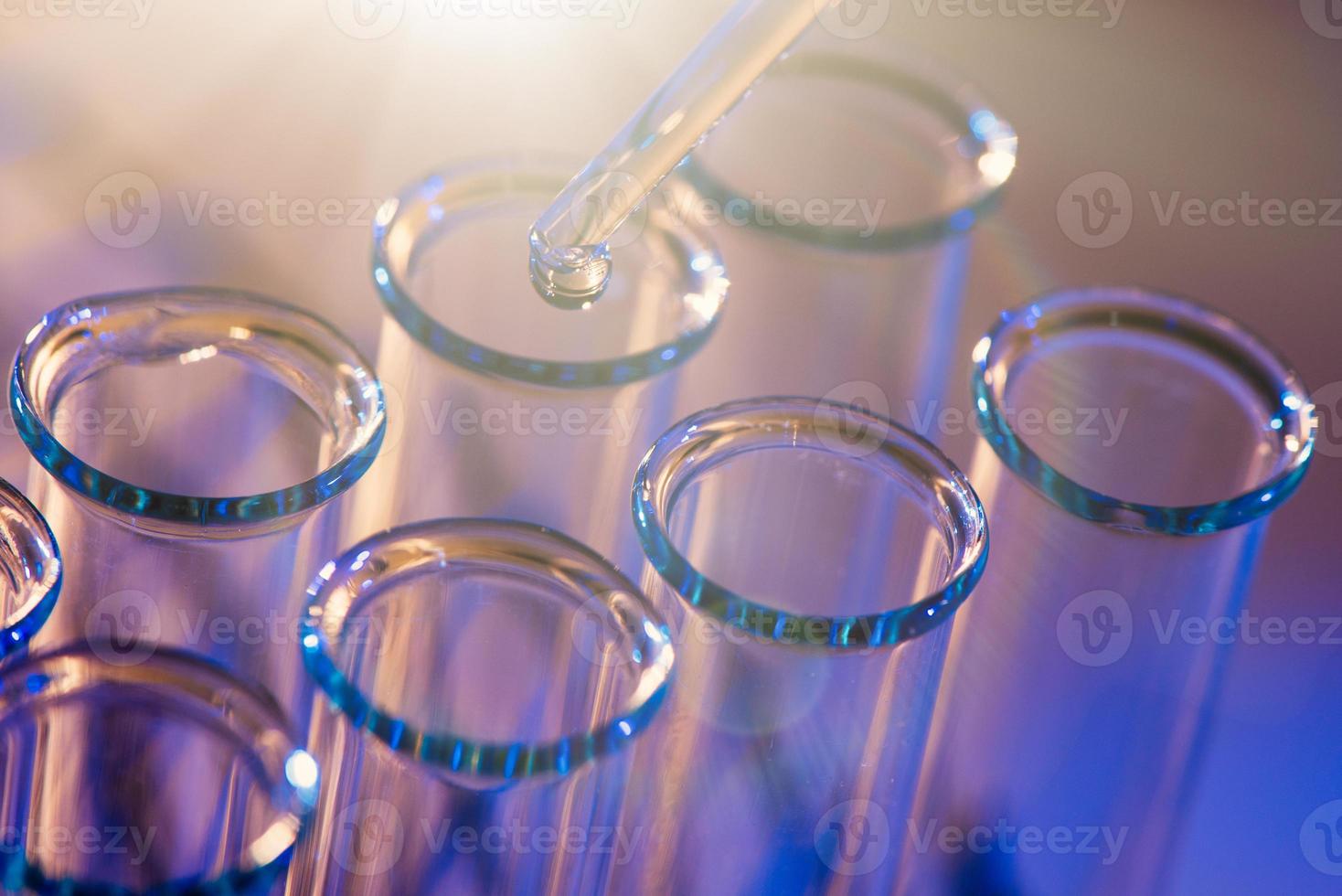 rangée de tubes à essai. concept de laboratoire médical ou scientifique, gouttelette de liquide avec compte-gouttes sur fond bleu rouge, gros plan, photo de micro photographie.