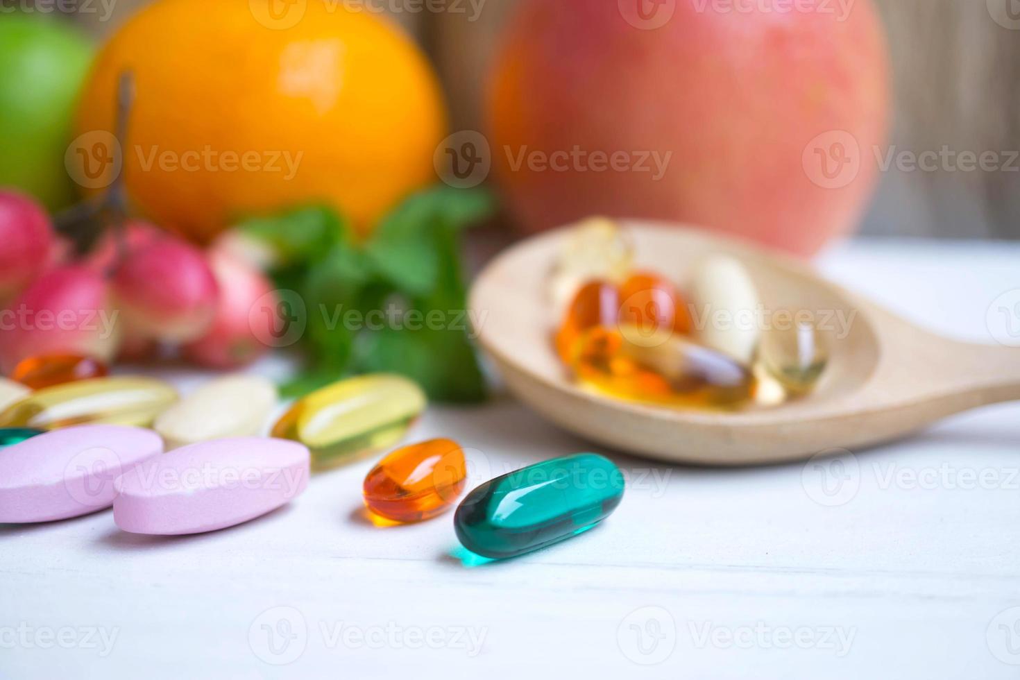 pilules et gélules dans une cuillère en bois avec des fruits frais.vitamines et supplément du concept de fruits. photo