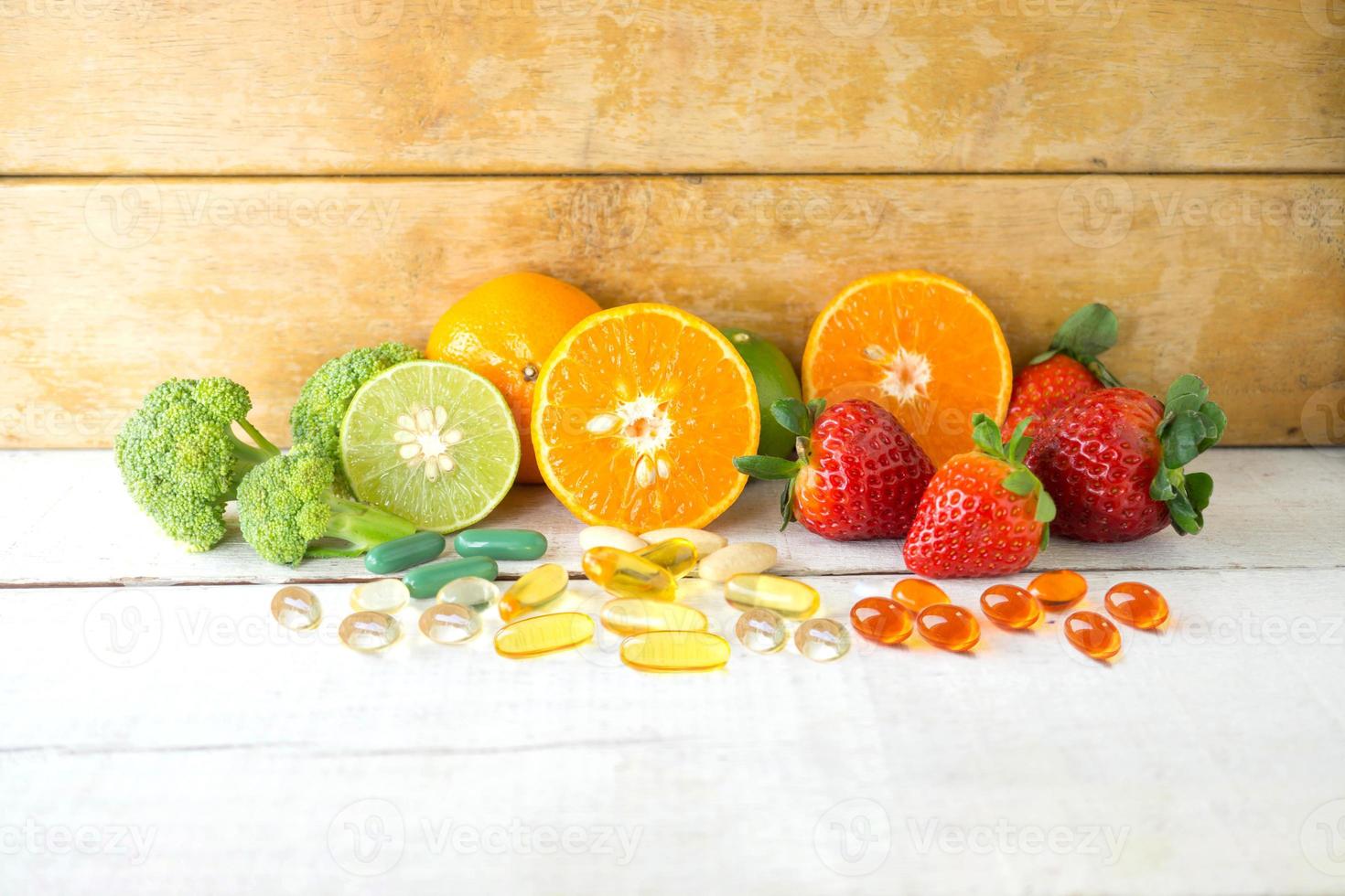 multivitamines et suppléments avec des fruits frais et sains sur fond de bois blanc. photo