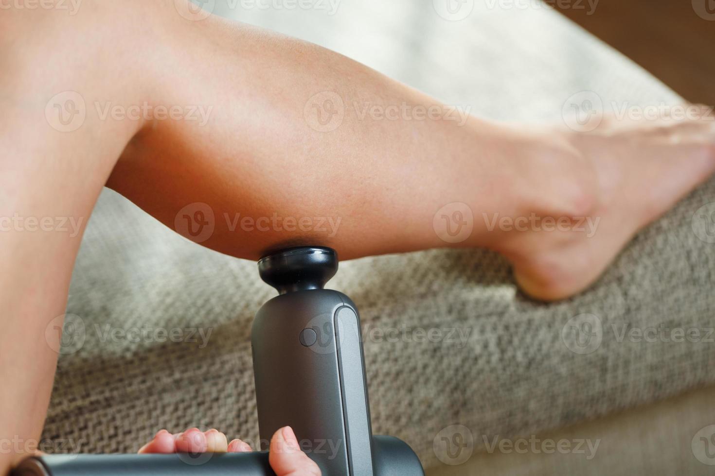 auto-massage des jambes des femmes avec un pistolet perfecteur à la maison. photo