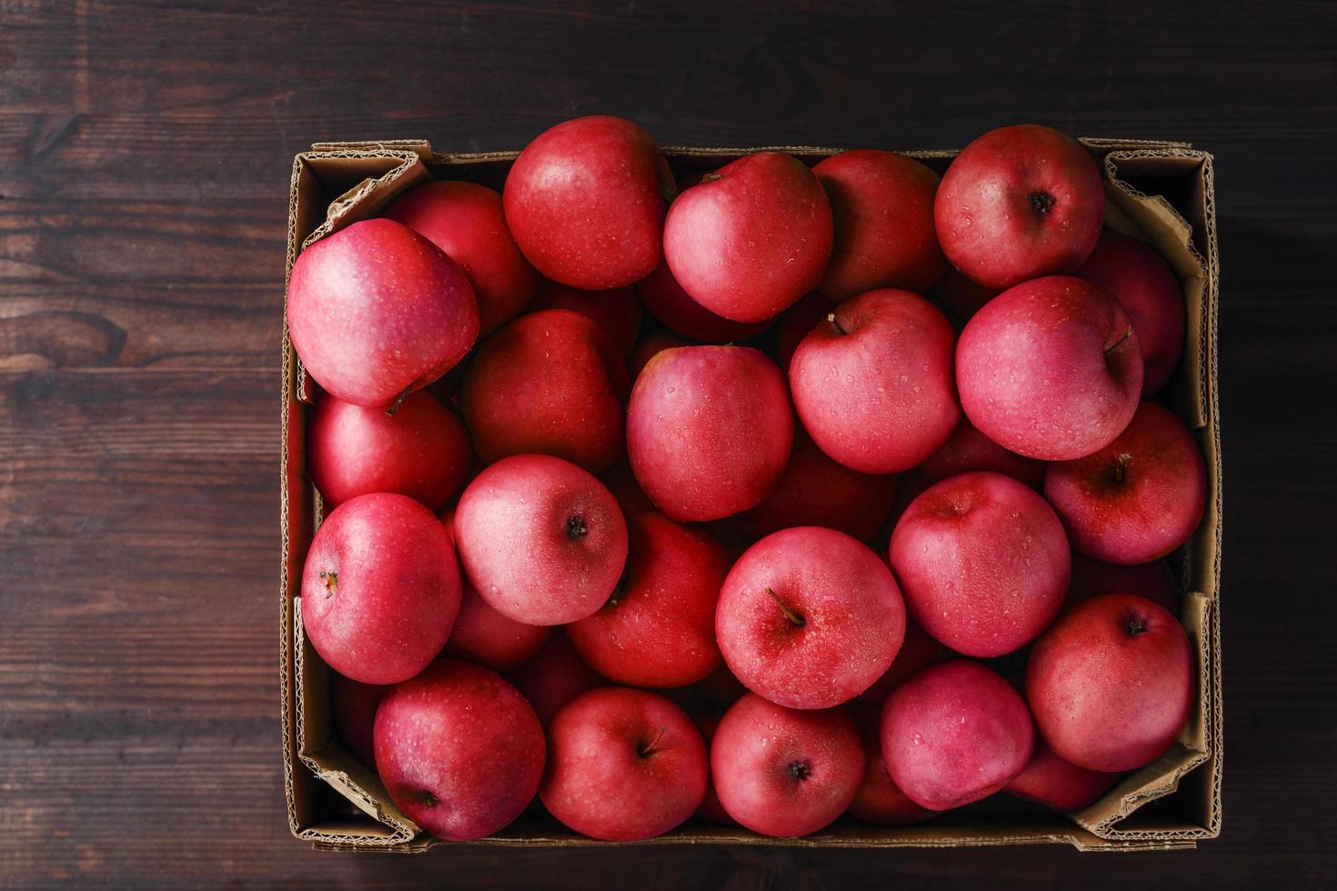 pommes rouges dans une boîte sur une table en bois, vue de dessus. photo