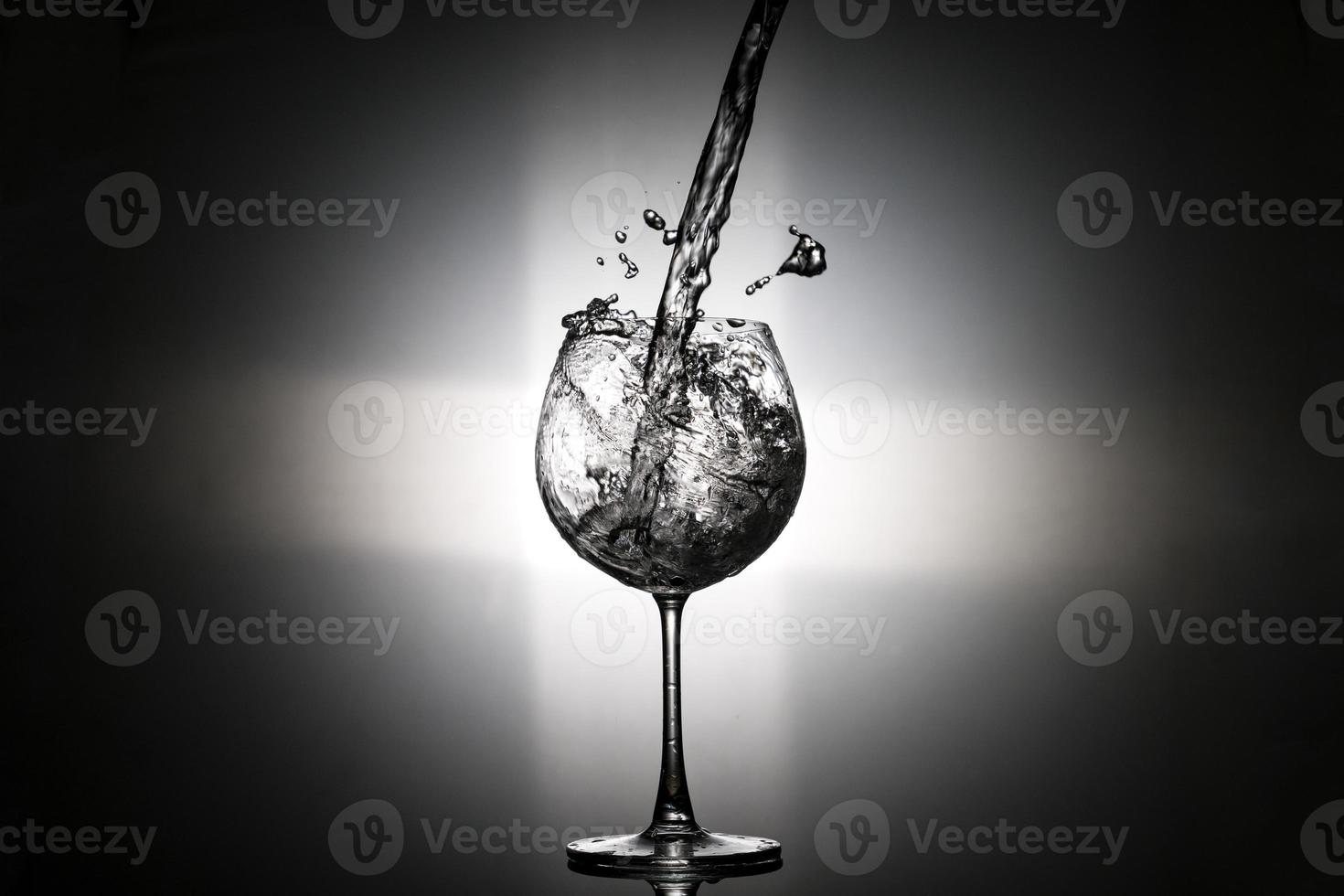 verser de l'eau dans le verre à vin avec feu arrière sur fond noir photo