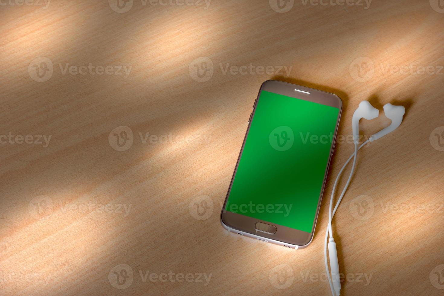 téléphone intelligent mobile et écouteur avec la lumière du soleil sur fond de bois photo