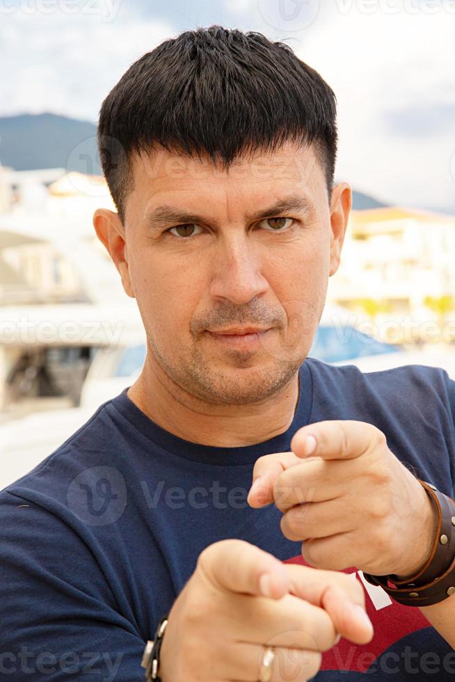 homme caucasien dans un t-shirt bleu pose près d'un yacht dans le port, tivat, monténégro. photo