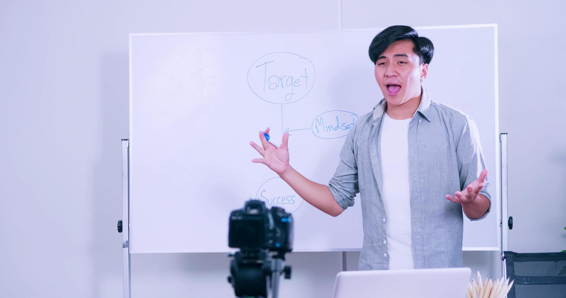 jeune homme asiatique diffusant en direct quelque chose par caméra pour le partage sur les réseaux sociaux. photo