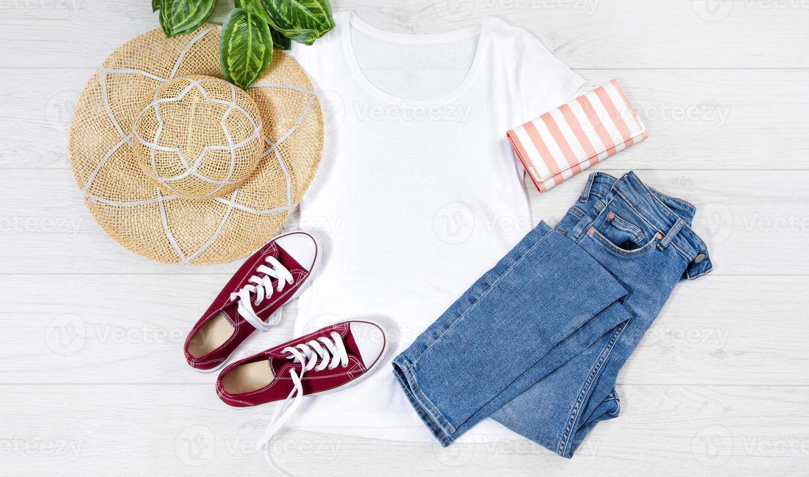 t shirt blanc et baskets. maquette de t-shirt à plat avec accessoires d'été. chapeau, jeans et baskets sur fond de plancher en bois. espace de copie. modèle de toile vierge. vue de dessus avant. photo