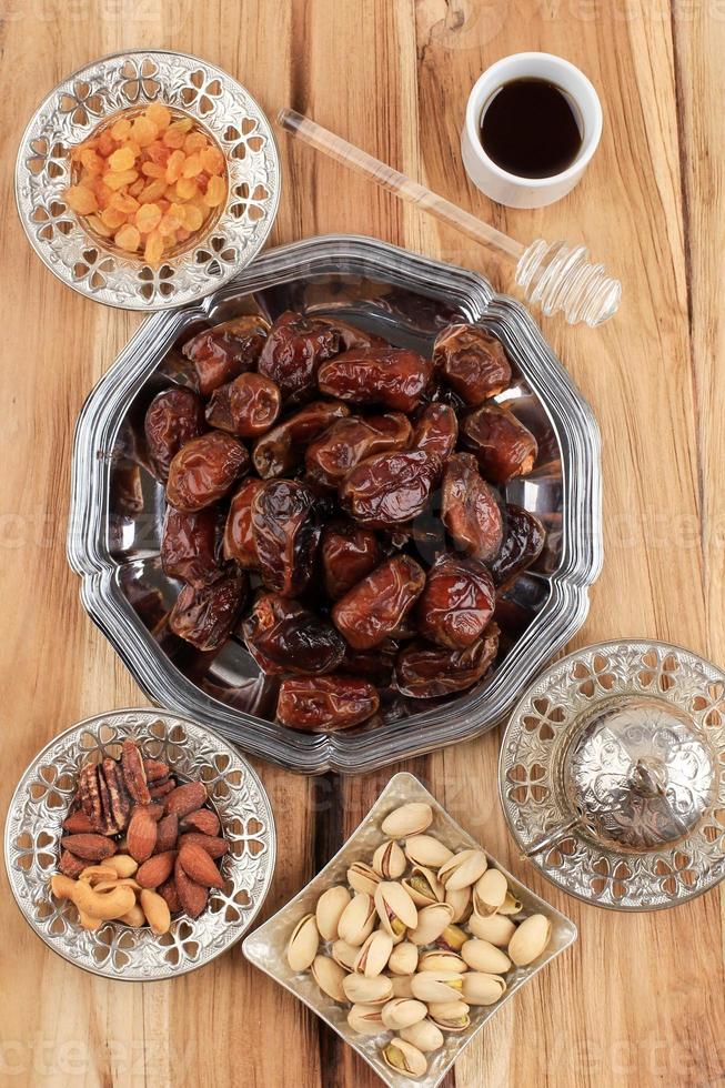 collation pour le ramadan ou l'aïd moubarak, fruits de dattes, amandes, raisins secs, miel et pistache photo