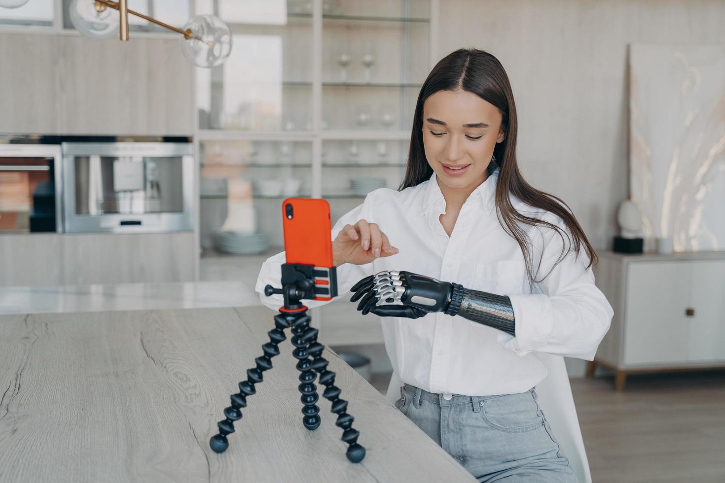 une jeune blogueuse beauté handicapée et séduisante filme une vidéo avec un smartphone à la maison. photo