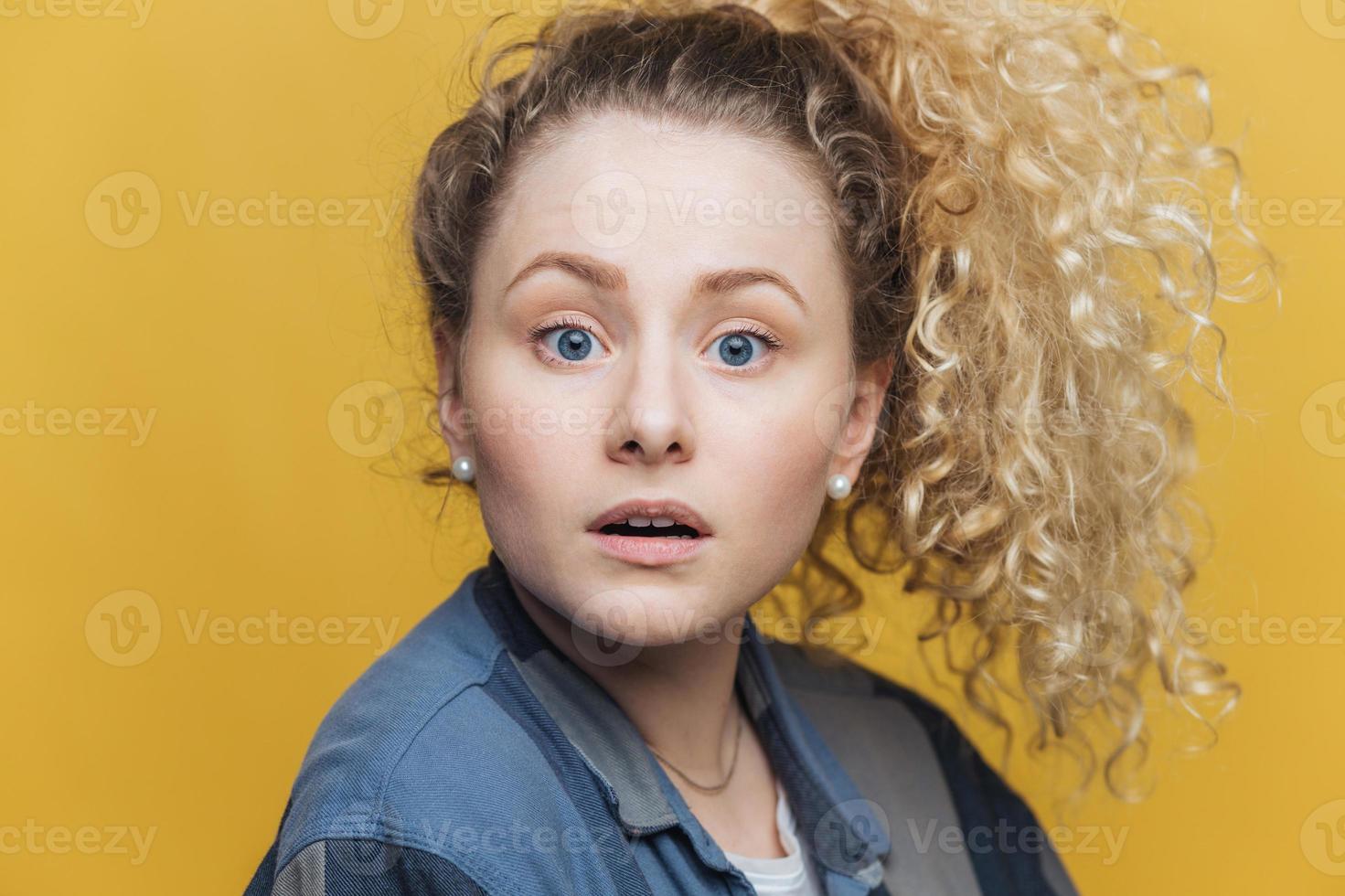 photo de tête d'une jolie femme aux yeux bleus dans la confusion, a une expression stupéfaite, ne peut pas comprendre ce qu'elle devrait faire, regarde avec perplexité directement dans la caméra, isolée sur fond jaune