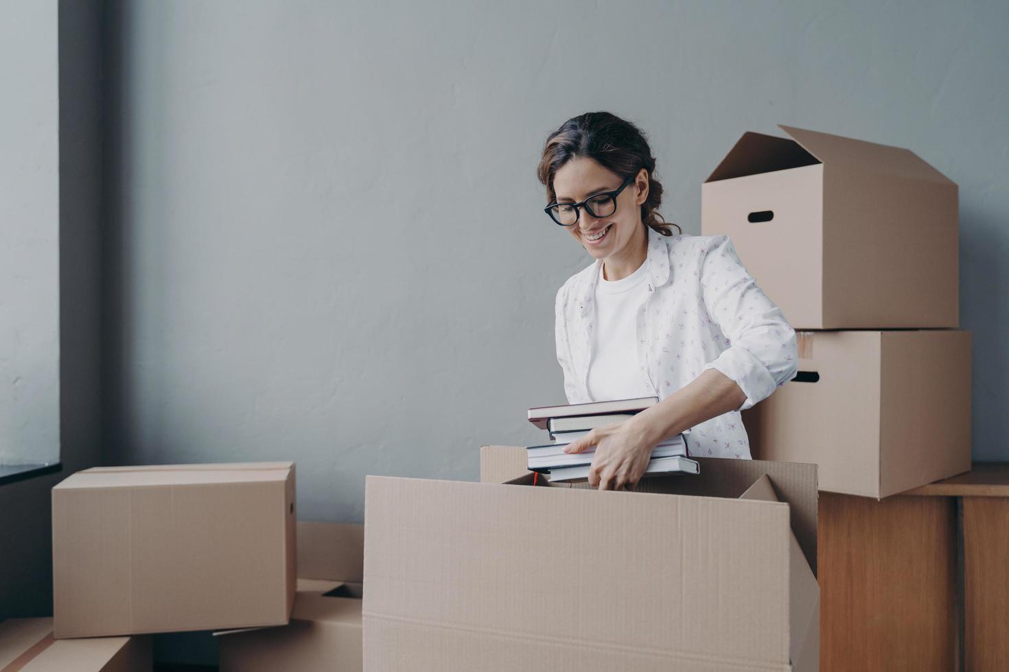 une jeune femme hispanique déballe des boîtes en carton et sort des livres. entrer à l'université. photo