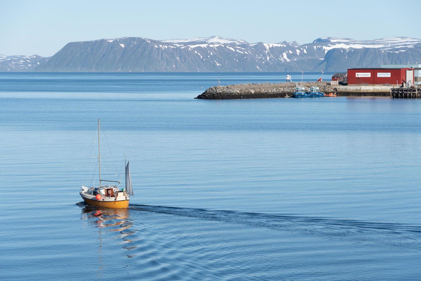 un voilier laissant un sillage sur l'eau calme alors qu'il quitte le port dans le nord de la norvège. photo