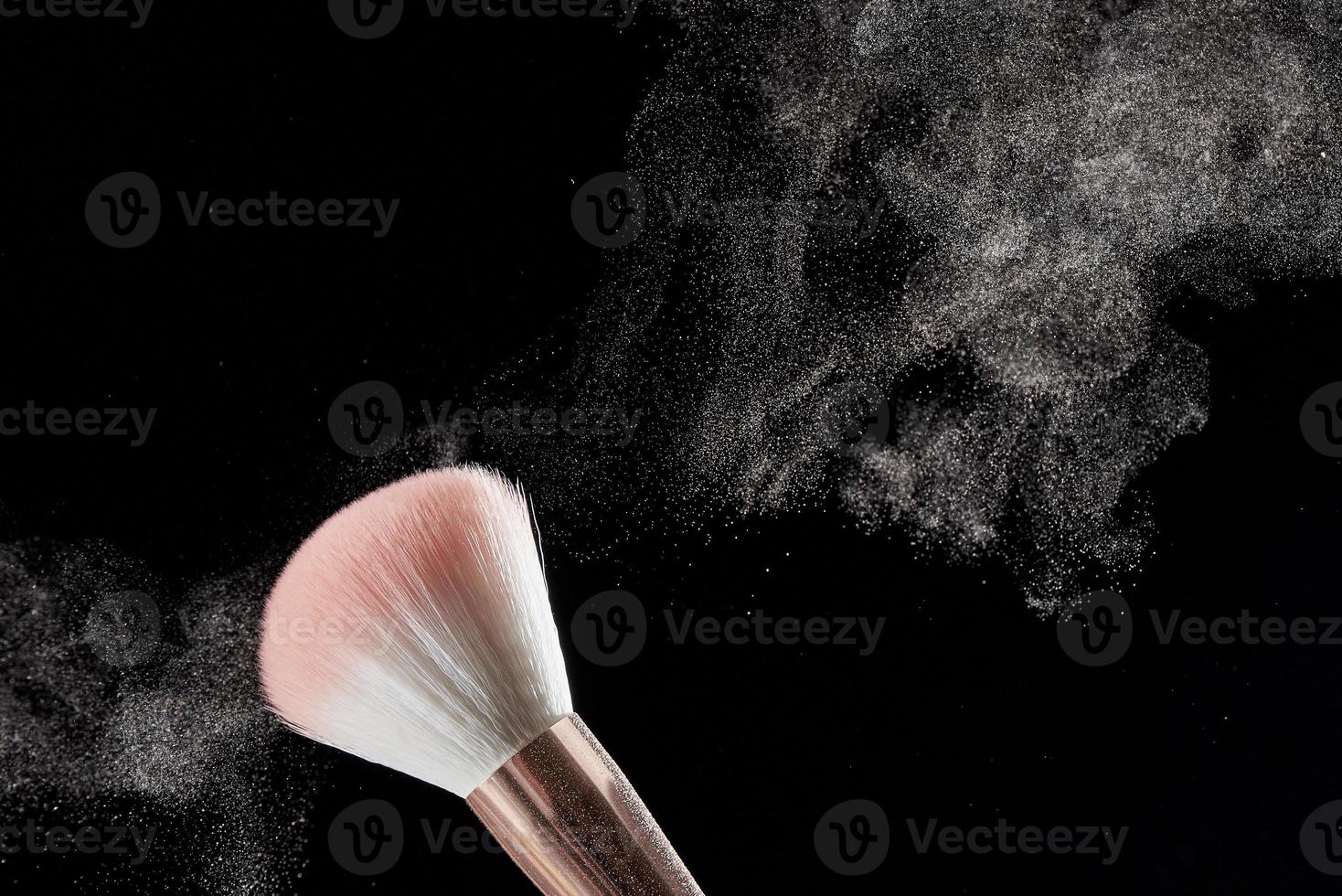 pinceau de maquillage avec poudre dessus et tas de poudre sur fond noir. photo avec espace de copie.