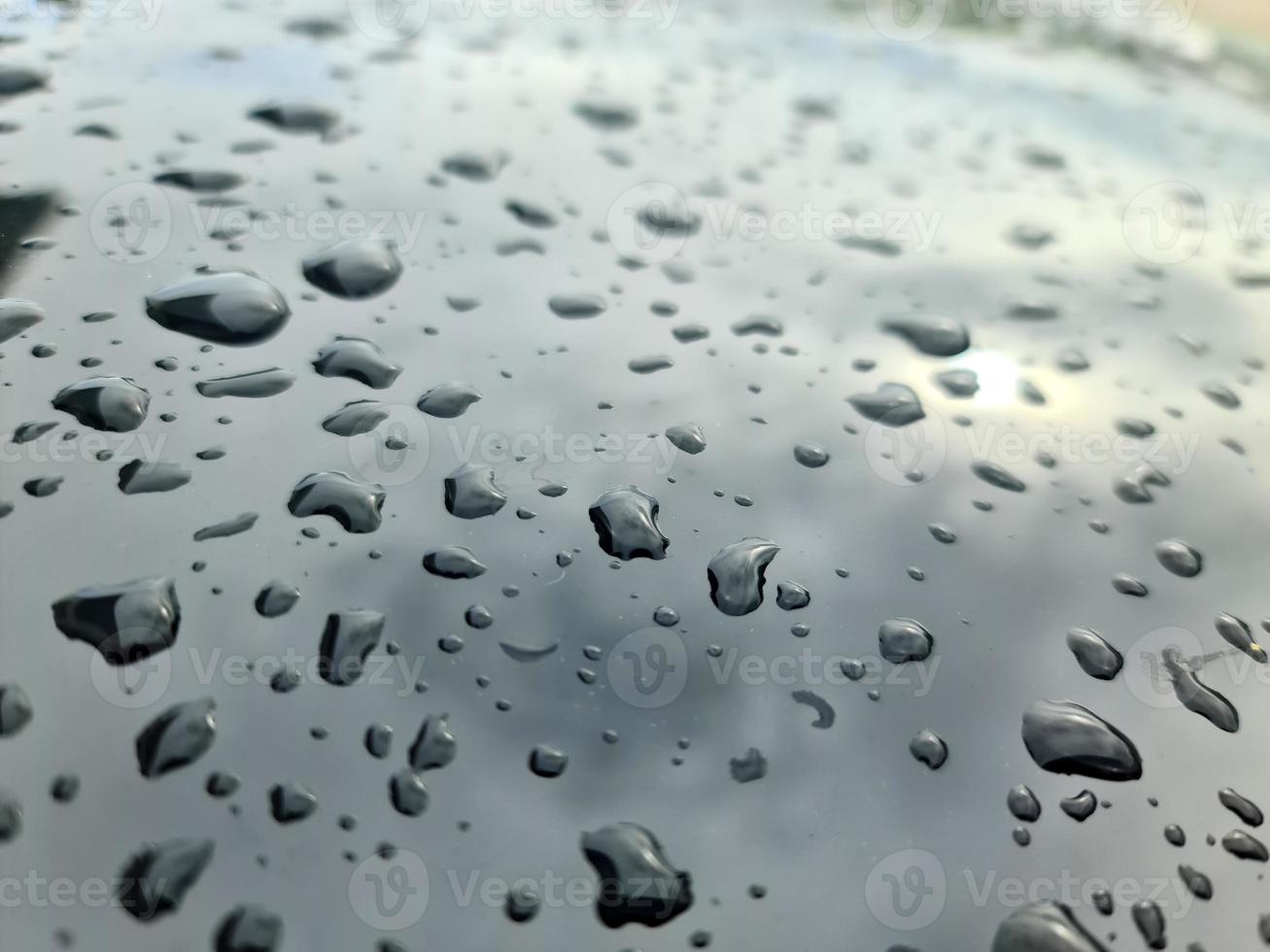 gouttes de pluie sur une surface de voiture métallique noire dans une vue rapprochée. photo
