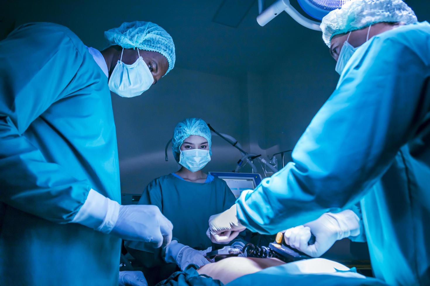 équipe de chirurgien médecin utilisant un défibrillateur pour donner un choc électrique au cœur du patient qui souffre d'un arrêt cardiaque dans la salle d'opération d'urgence pour le concept de soins de santé photo