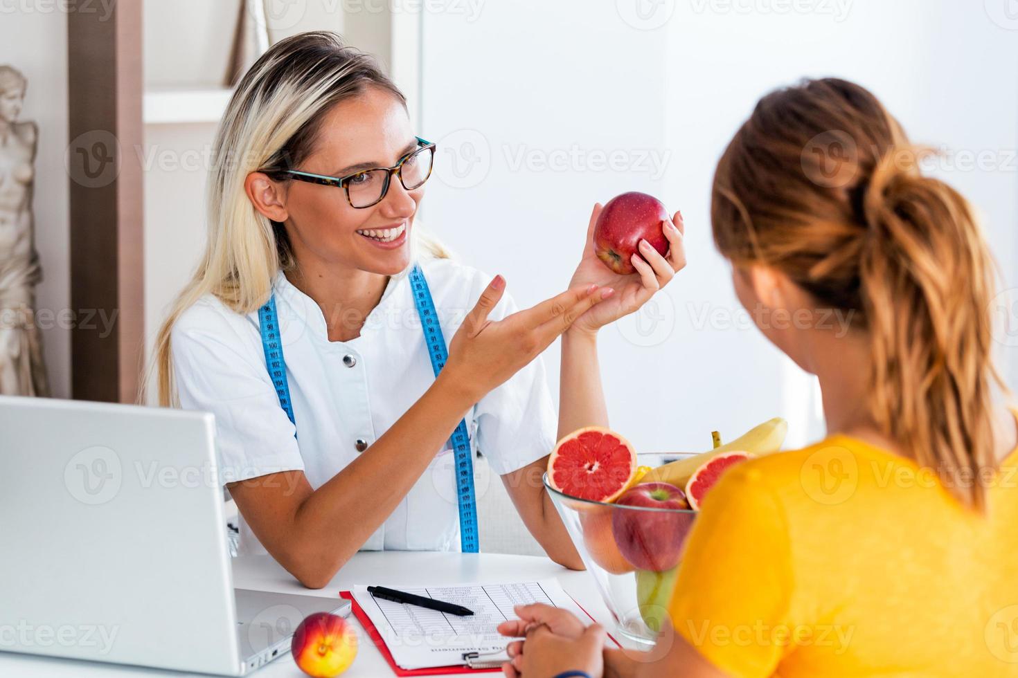 portrait d'une jeune nutritionniste souriante dans la salle de consultation. faire un plan de régime. jeune femme visitant une nutritionniste dans une clinique de perte de poids photo