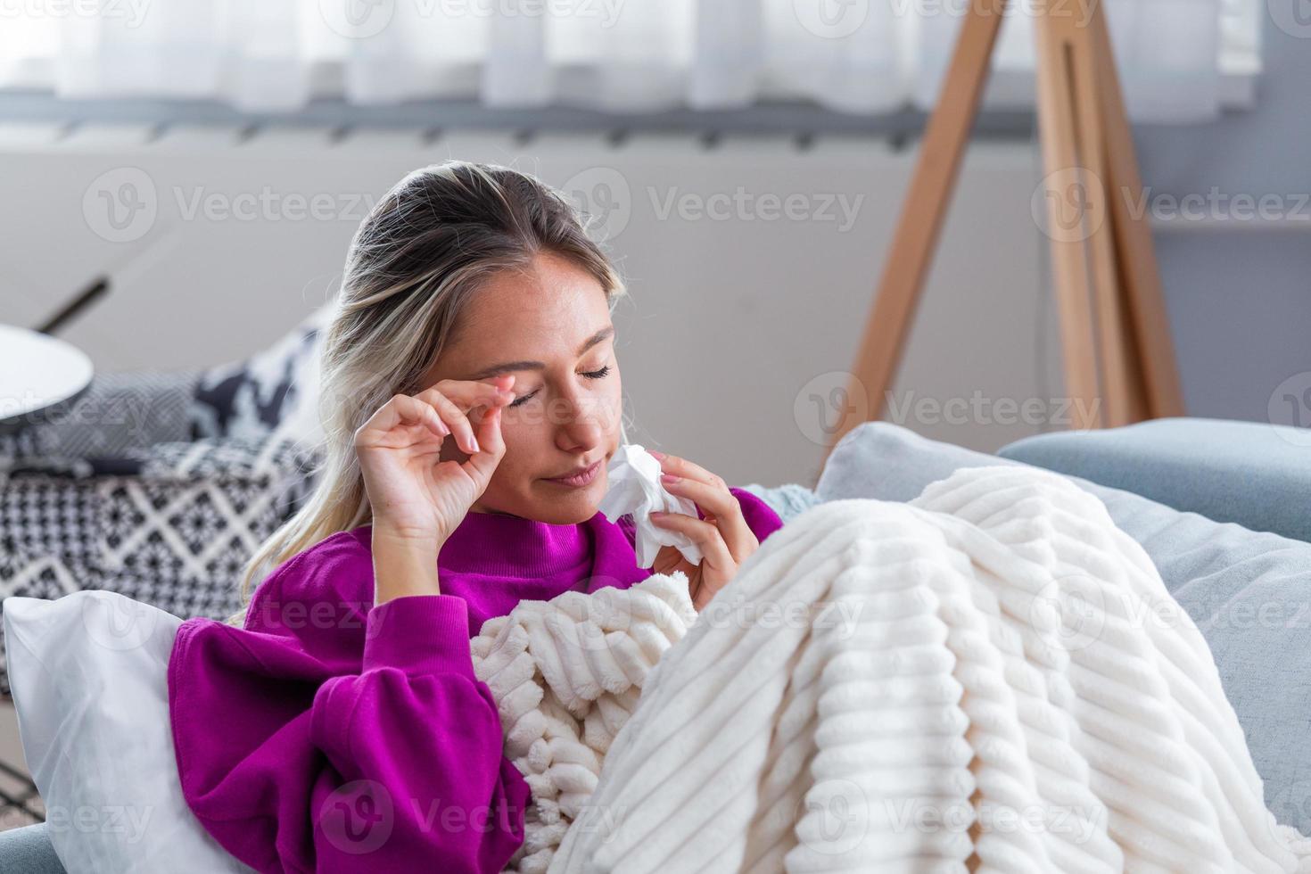 femme déprimée et triste qui pleure seule à la maison. fille au cœur brisé assise sur un canapé, pleurant, utilisant des mouchoirs. une femme a attrapé un rhume ou une grippe. portrait d'une fille malsaine ressentant de la douleur photo