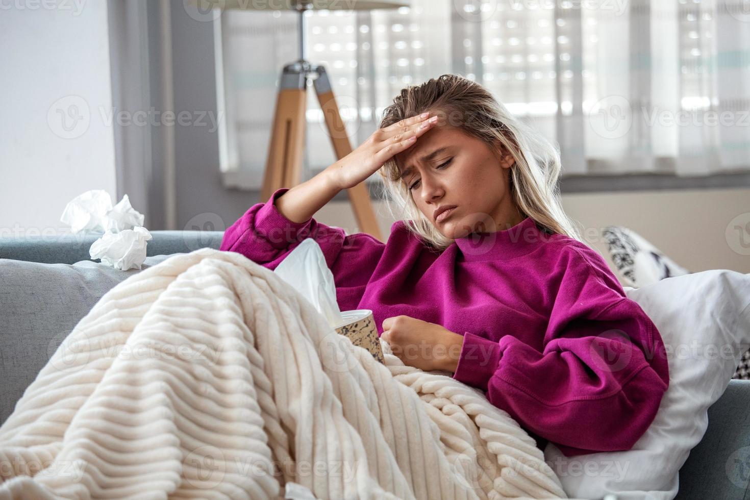 femme malade avec des maux de tête assis sous la couverture. femme malade avec des infections saisonnières, grippe, allergie au lit. femme malade recouverte d'une couverture allongée dans son lit avec une forte fièvre et une grippe, se reposant. photo