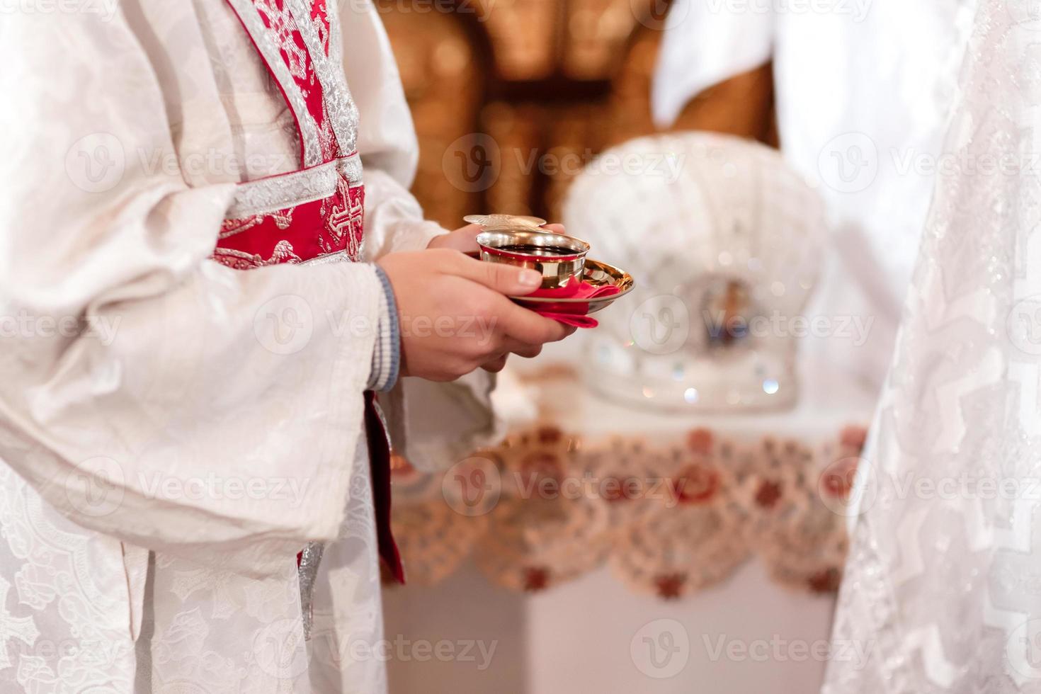 le prêtre bénit et tient en coupe le sang de dieu, le vin. prêtre célèbre une messe à l'église. cérémonie de mariage traditionnelle. coupe sacrée pour la cérémonie de mariage. photo de haute qualité
