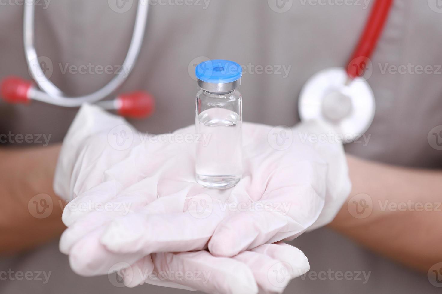 femme médecin avec un stéthoscope sur l'épaule tenant le vaccin covid-19. concept de soins de santé et médical. développement et création d'un vaccin contre le coronavirus. photo