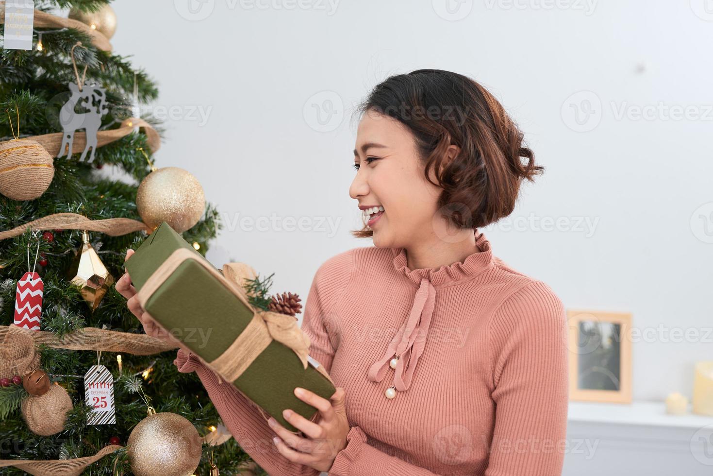 heureuse jeune femme aux cheveux bouclés, cadeaux près de l'arbre de noël. notion de nouvel an. photo