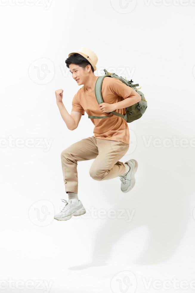 heureux jeune homme voyageant sautant isolé sur blanc. photo