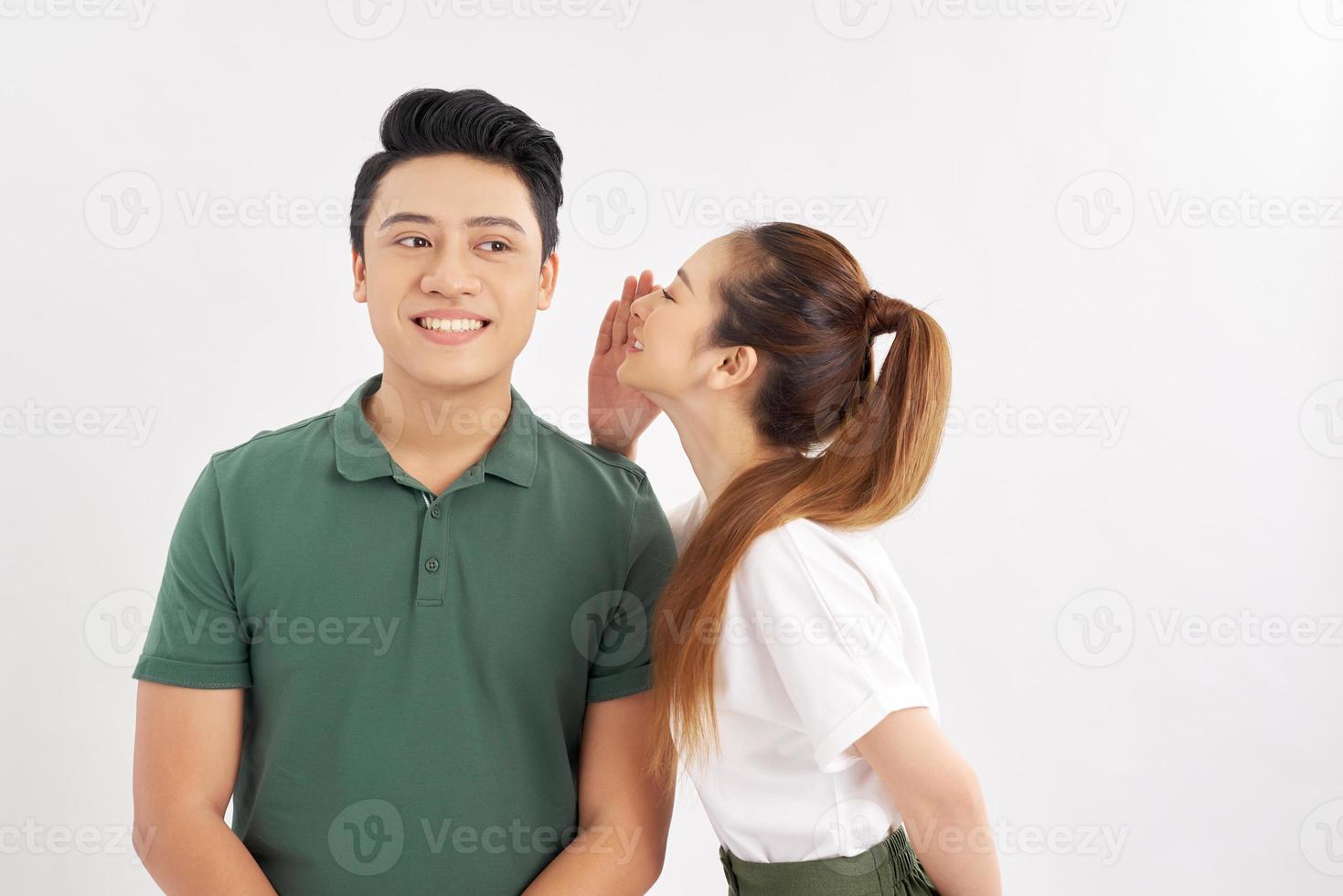 jeune fille chuchotant à son petit ami sur fond blanc photo