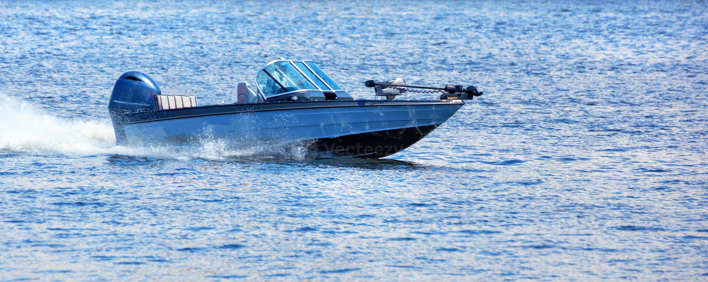 un bateau à moteur se précipite rapidement le long des eaux de la rivière par une journée d'été ensoleillée. photo