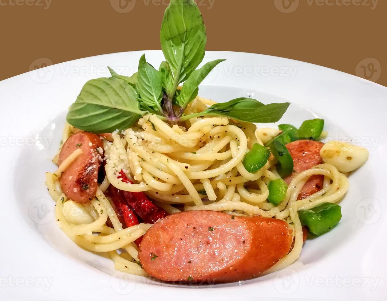Spaghetti à la saucisse thaïlandaise fusion gros plan sur plaque en céramique blanche et fond marron.. photo