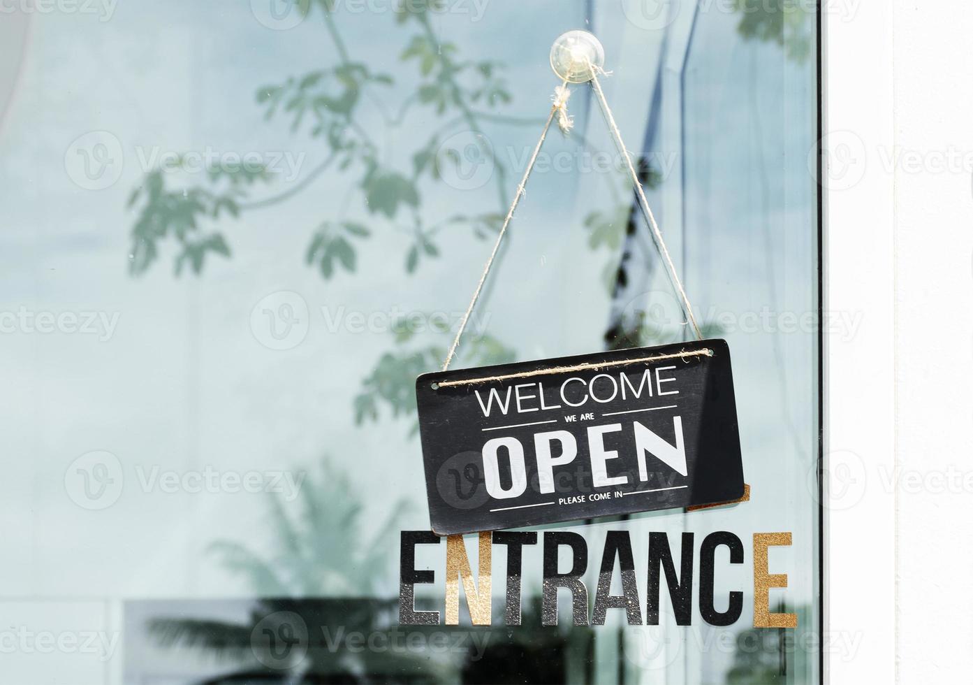 Panneau suspendu avec message de bienvenue ouvert sur la porte vitrée du café photo