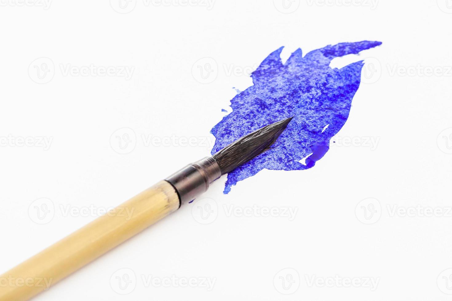 Pointe de pinceau peinte en bleu dans la tache en gros plan photo