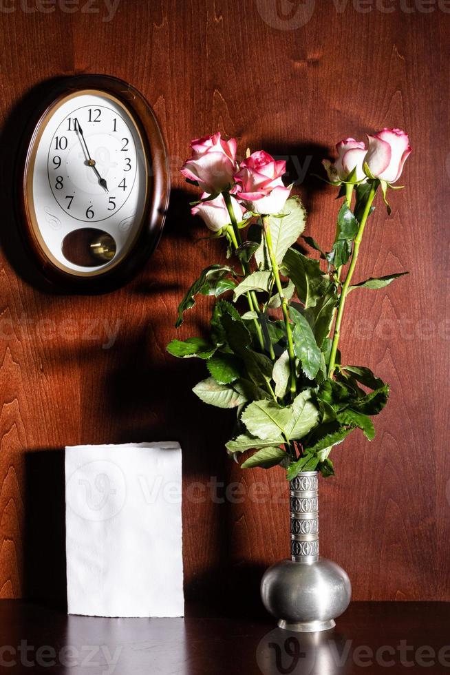 horloge murale, feuille de papier vierge et roses roses photo