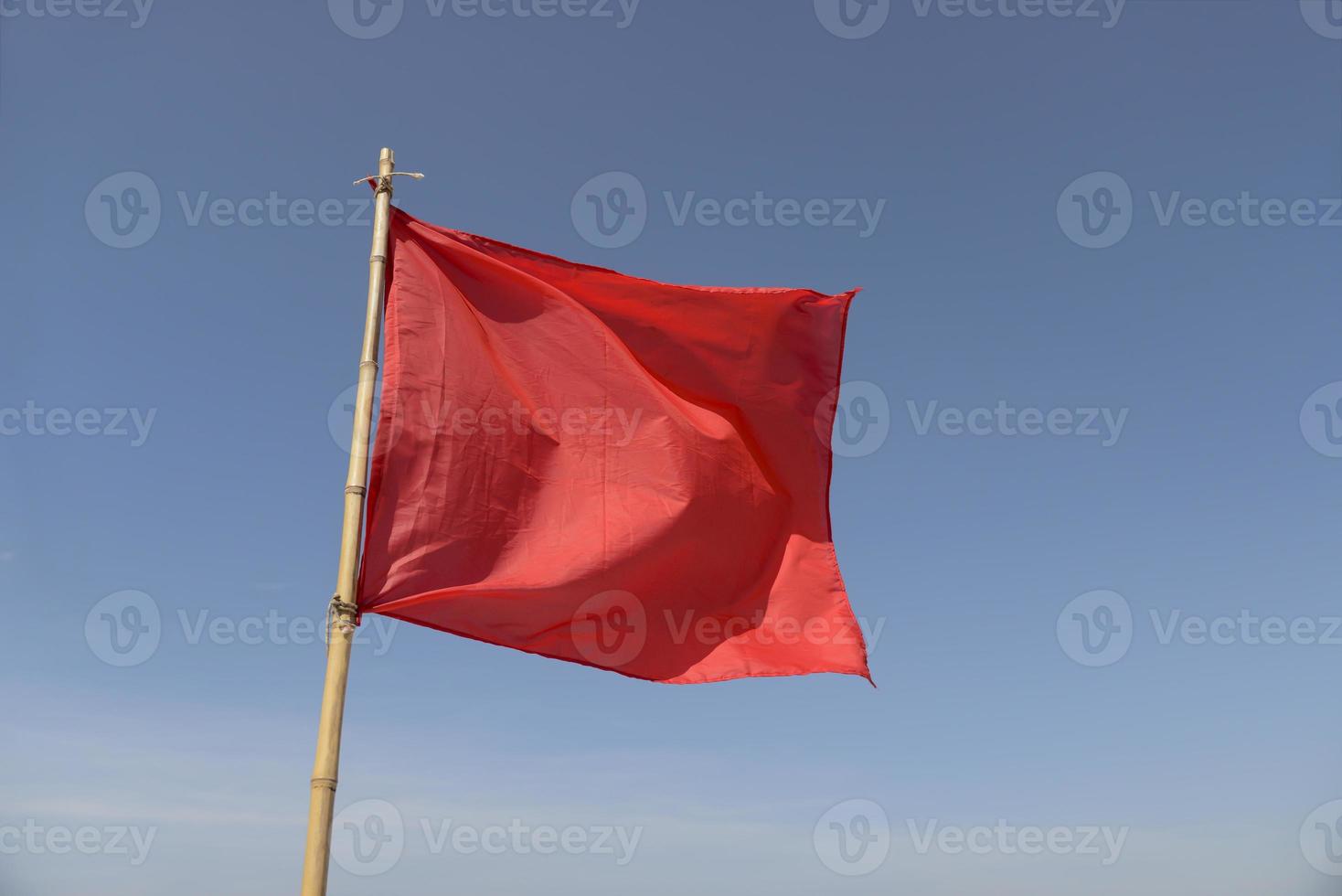drapeau rouge se balançant au vent sur un fond de ciel bleu photo