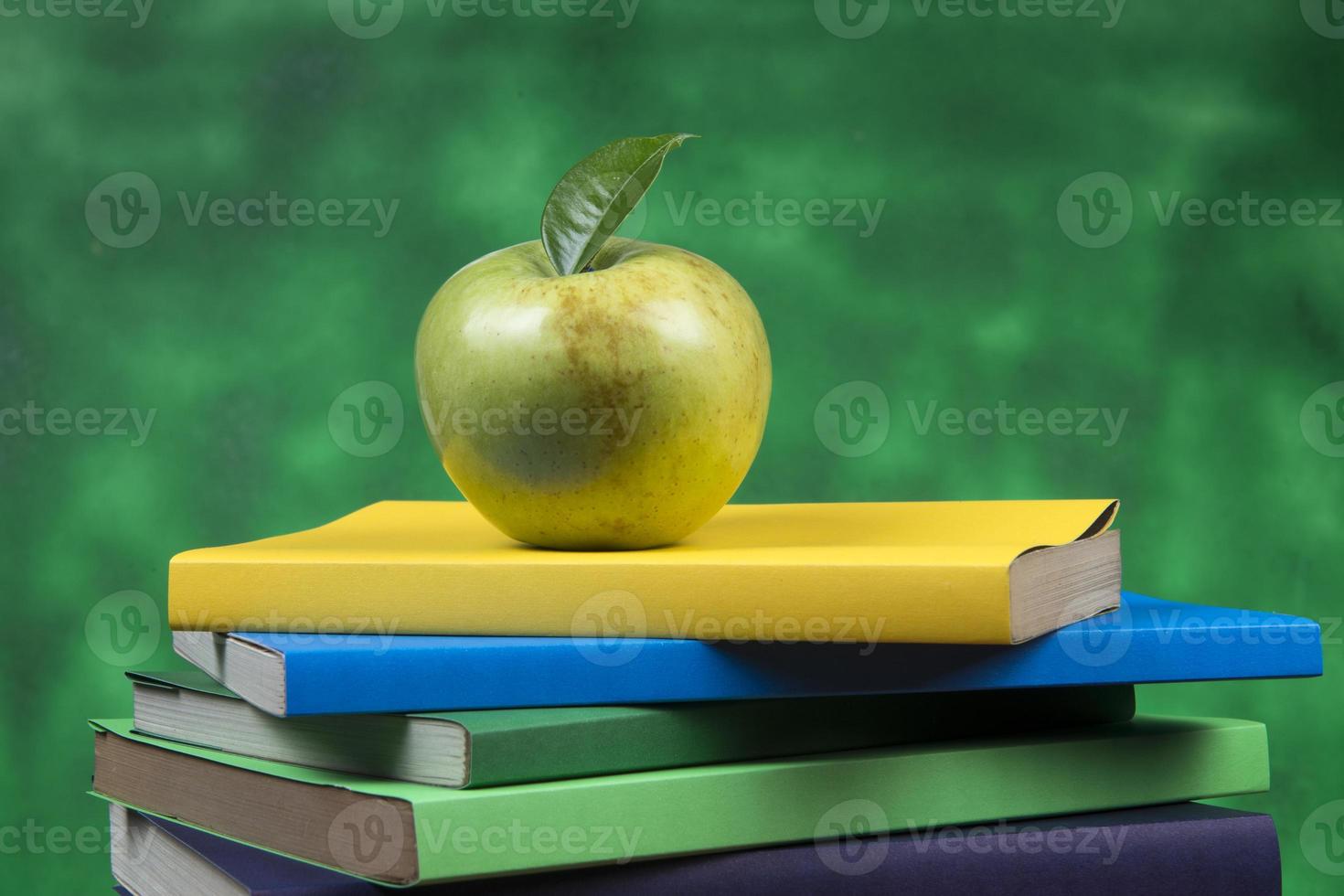 pomme sur le dessus d'une pile de livres, au dos des classes d'école. photo