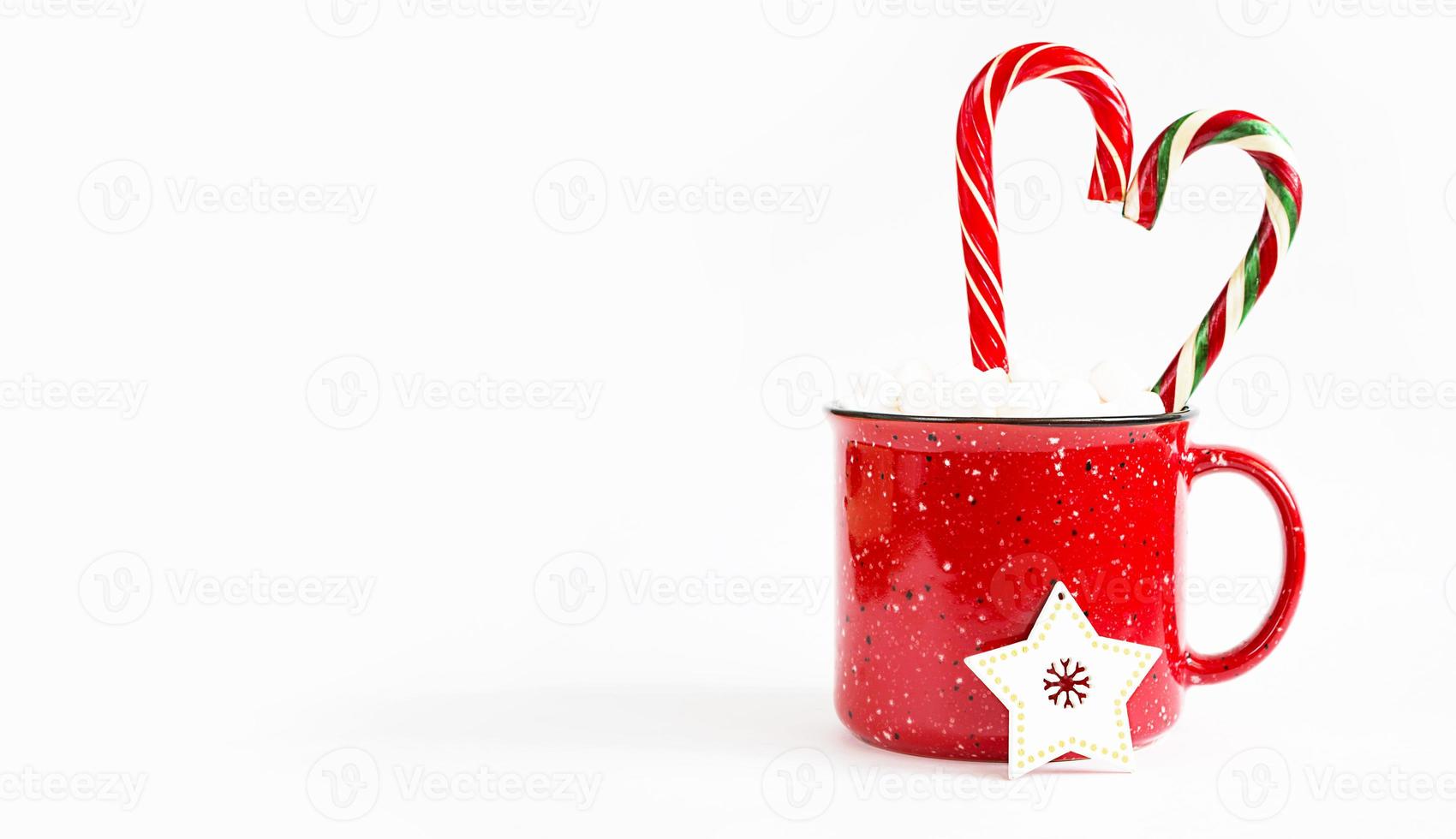 tasse rouge avec des guimauves et une canne en bonbon au caramel en forme de coeur sur fond blanc et un arbre de noël jouet une étoile en bois. noël, nouvel an, ambiance festive. copie espace photo