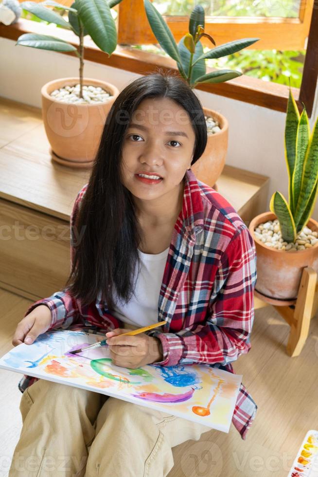 jeune fille assise sur le sol et peignant sur papier à la maison. passe-temps et étude d'art à la maison. photo