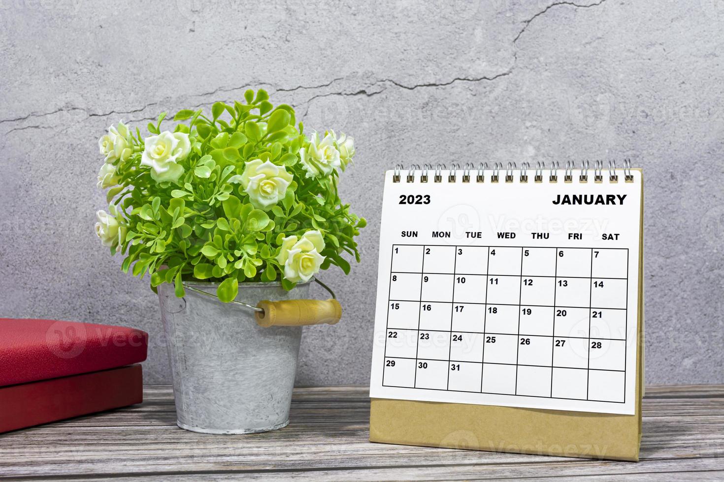 calendrier de bureau de janvier 2023 sur un bureau en bois avec plante en pot et livres. photo