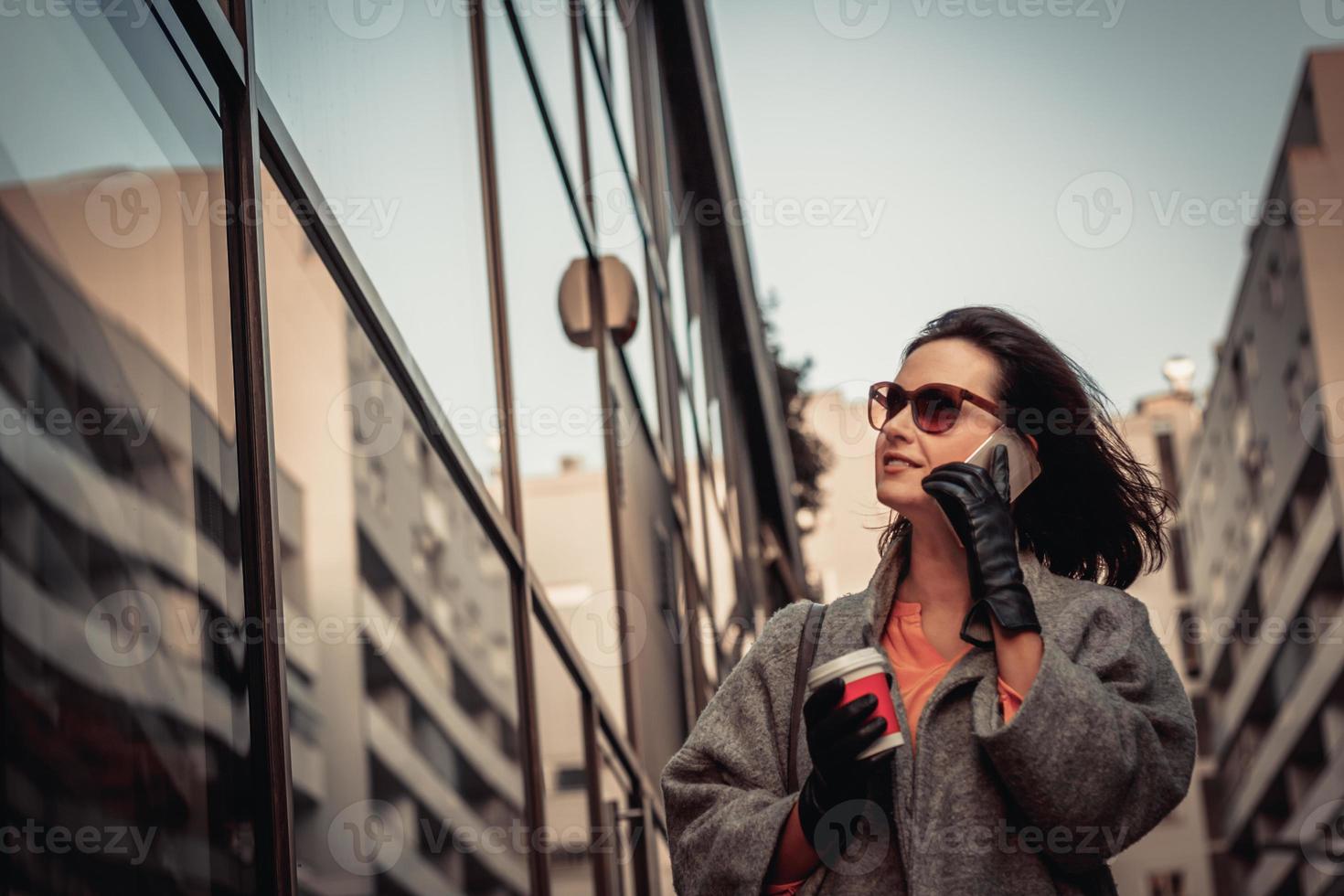 femme à la mode faisant du lèche-vitrines et parlant au téléphone. photo