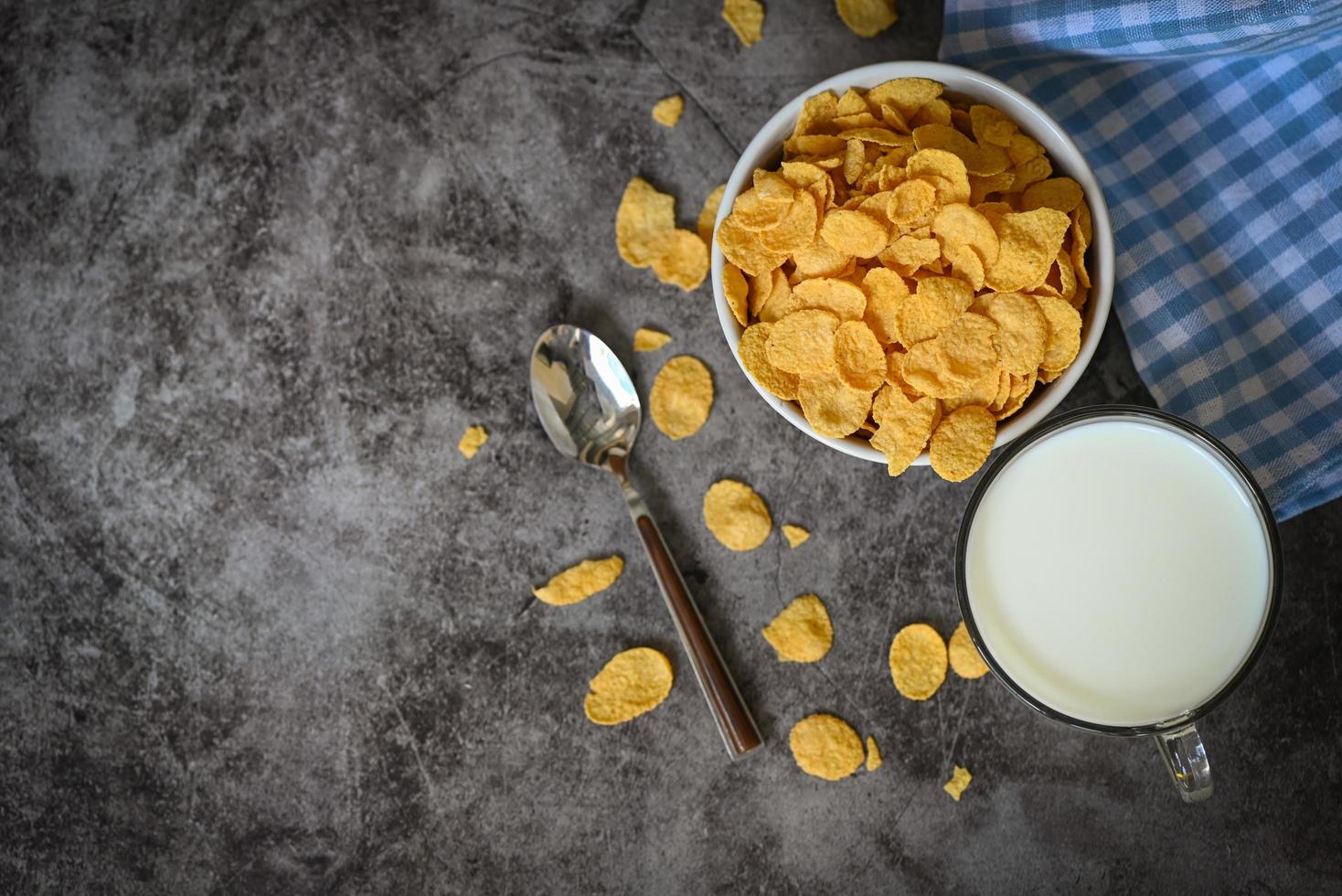 cornflakes bol petit-déjeuner et collation pour un concept d'alimentation saine, petit-déjeuner matinal céréales complètes fraîches, cornflakes avec du lait sur fond sombre photo