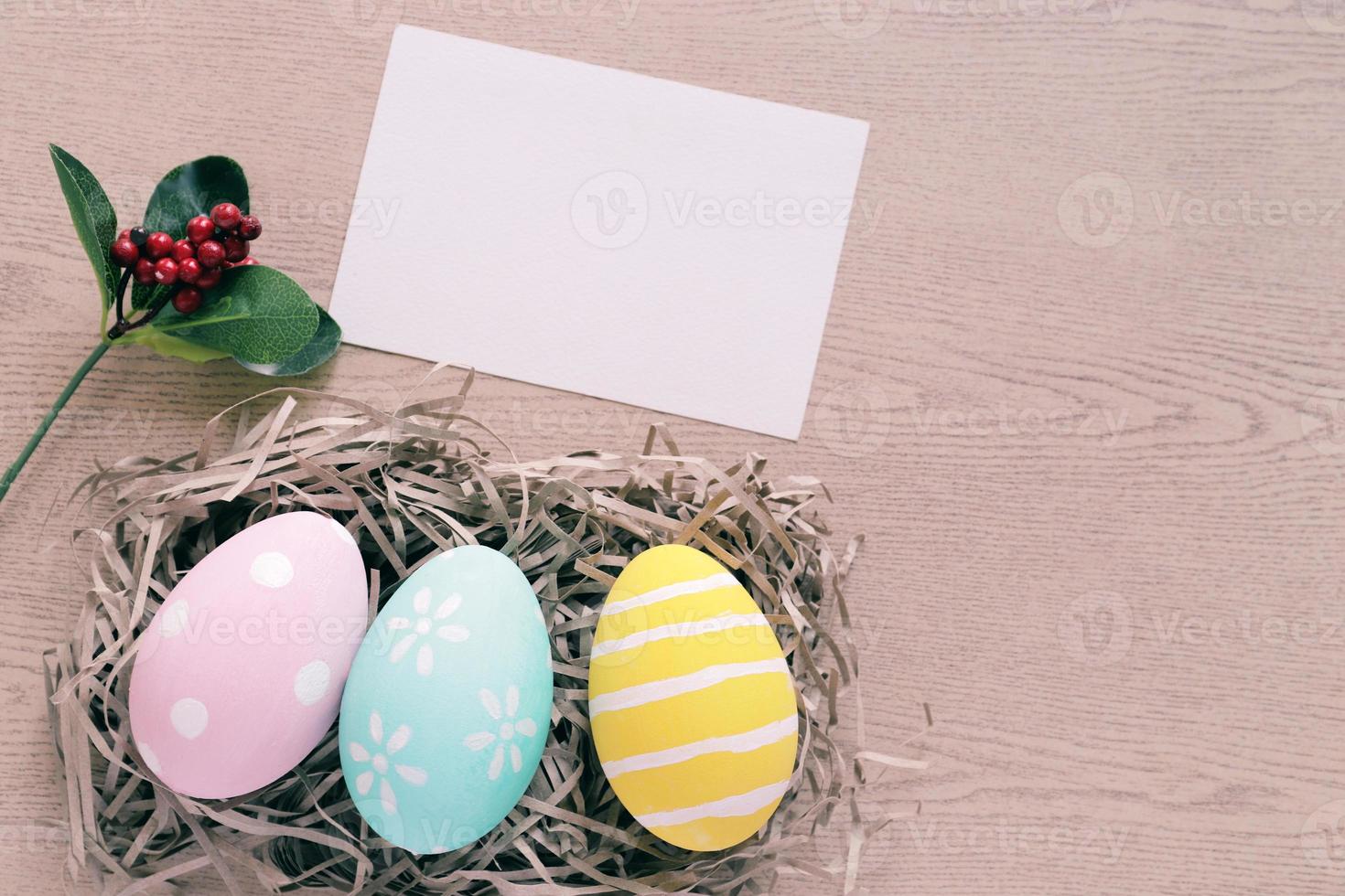 Oeufs de pâques pastel et colorés dans le nid avec carte vierge sur fond de bois, concept de joyeuses fêtes de pâques photo