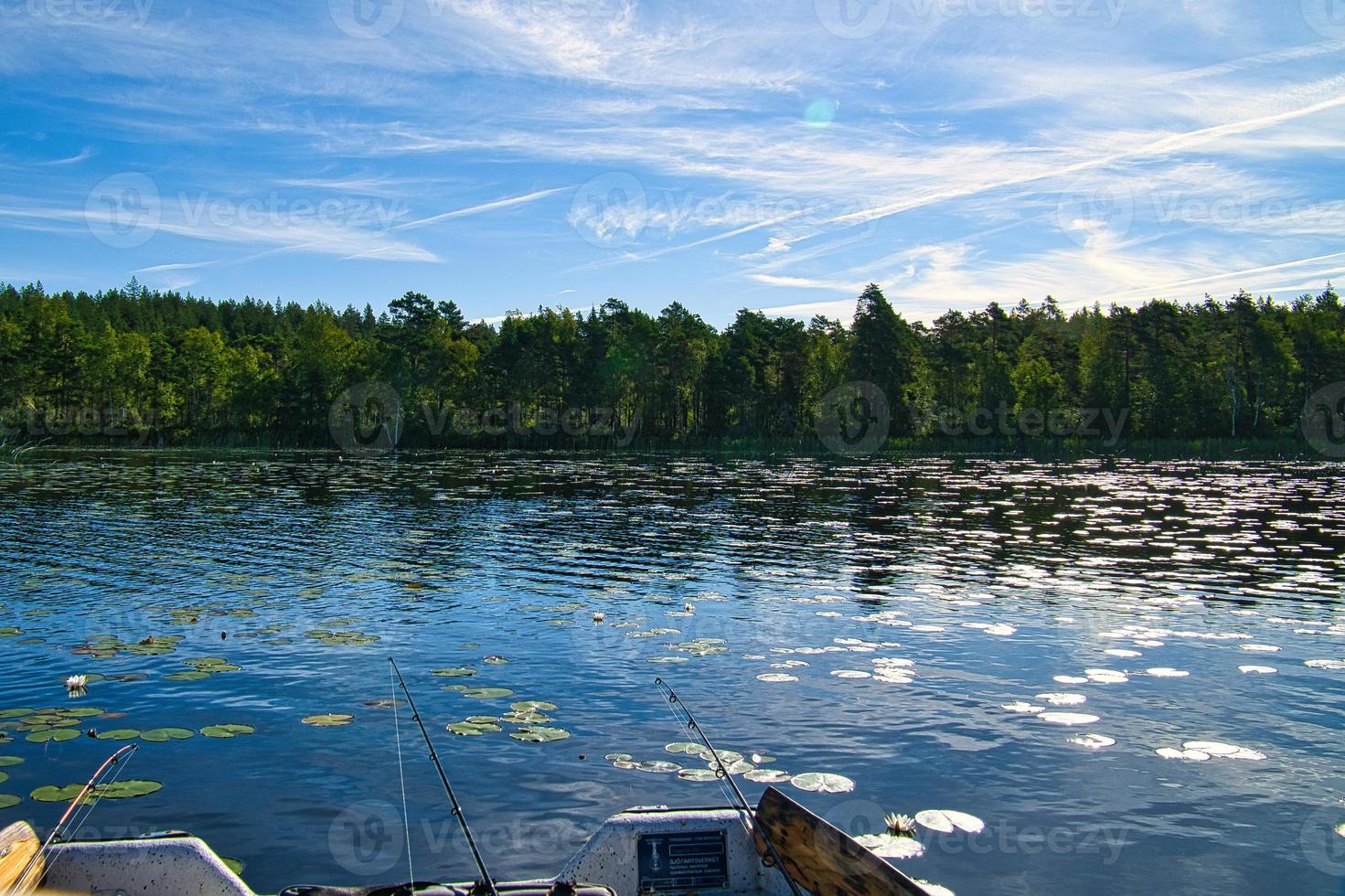 un bateau de pêche sur un lac en suède à smalland. eau bleue, ciel ensoleillé, forêts photo