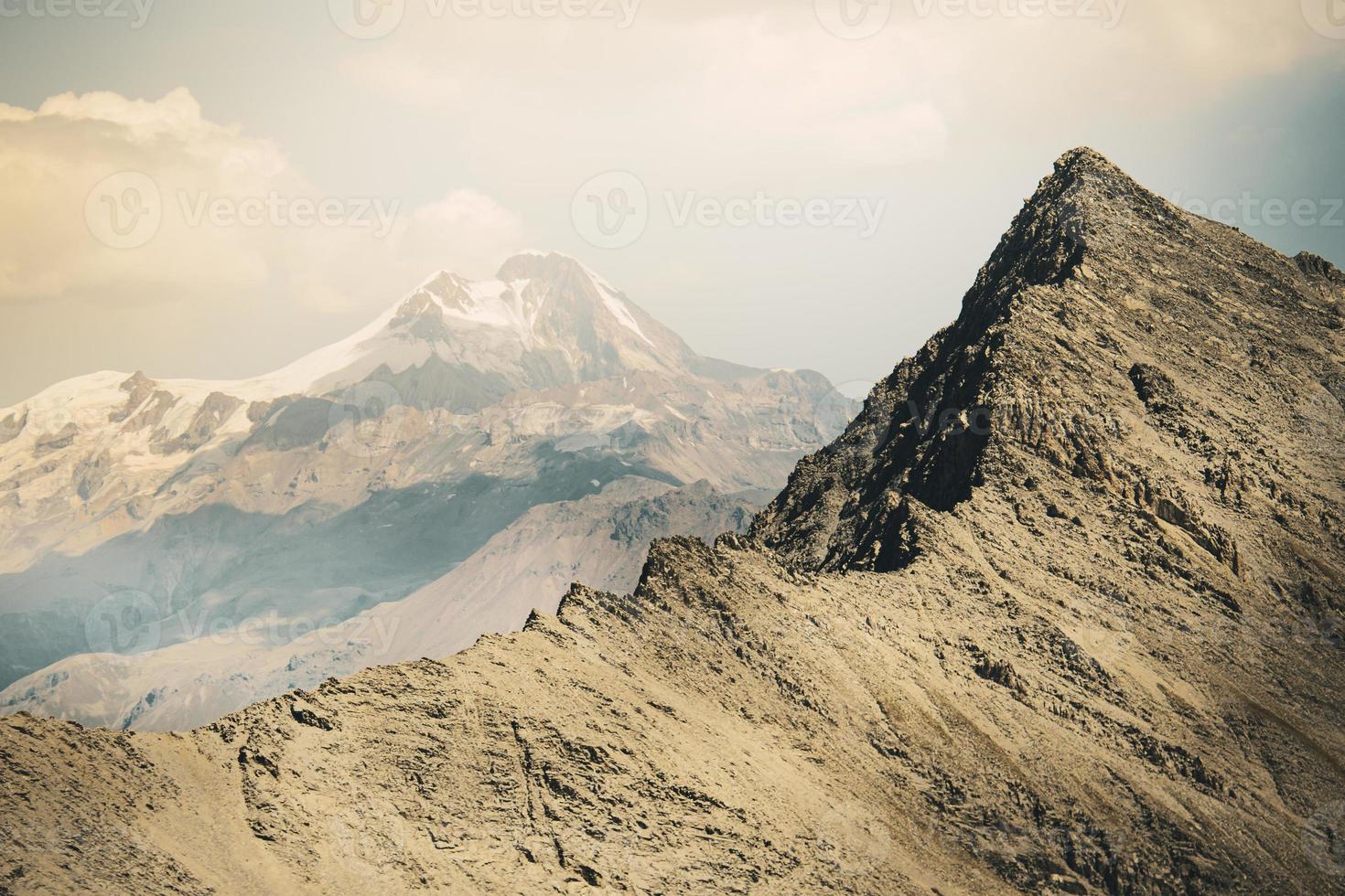 sommet enneigé du pic kazbek entouré par les montagnes au printemps. paysages spectaculaires du parc national de kazbegi. randonnée et escalade dans le caucase.deda ena panorama photo