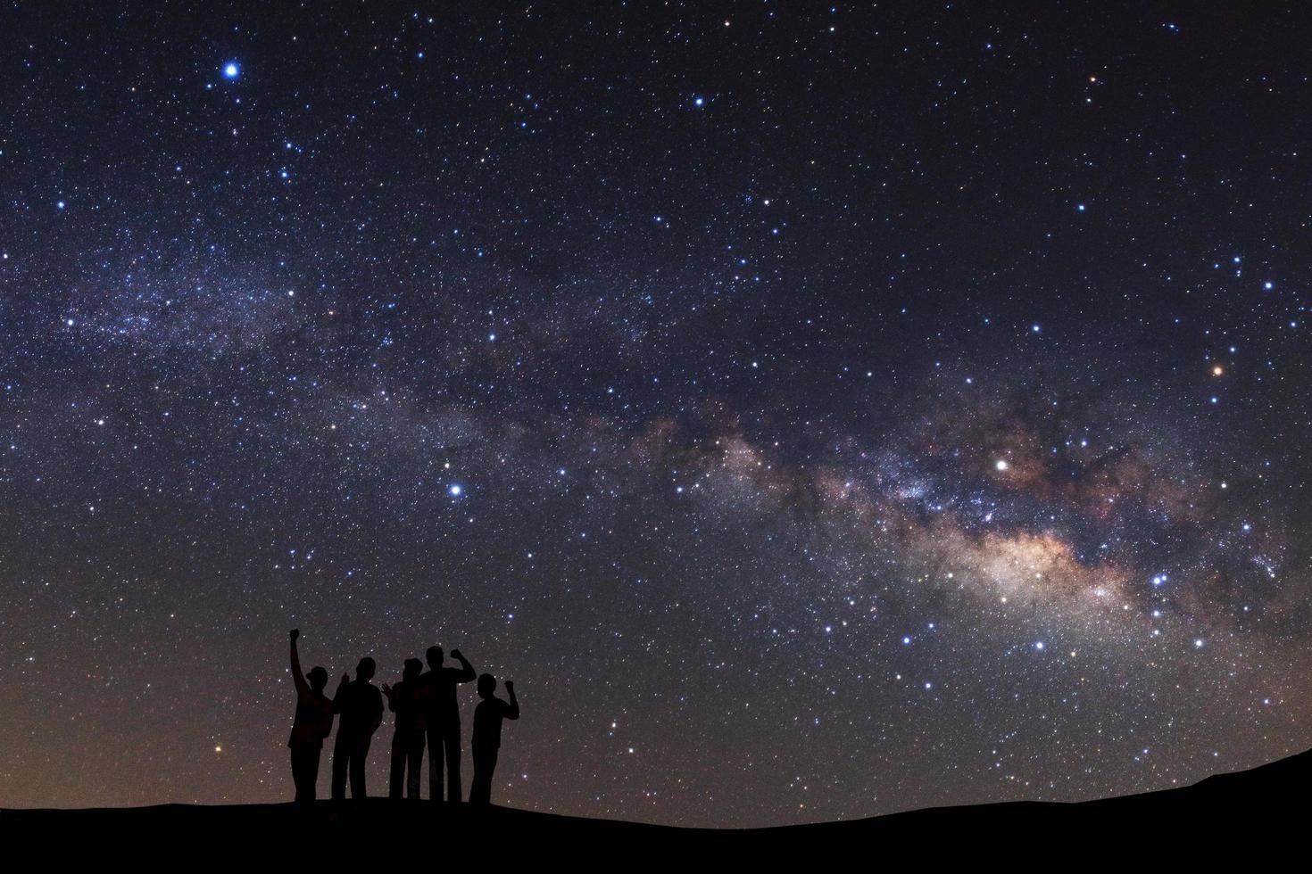 paysage avec voie lactée, ciel nocturne avec étoiles et silhouette d'un homme sportif debout avec les bras levés sur la haute montagne. photo