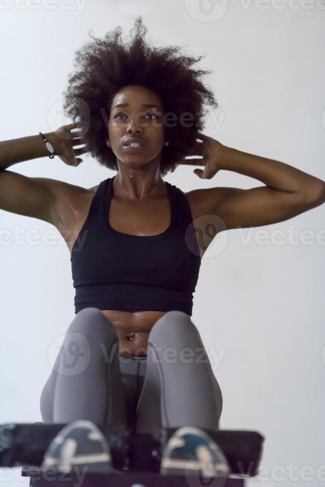 femme noire faisant des redressements assis à la salle de gym photo