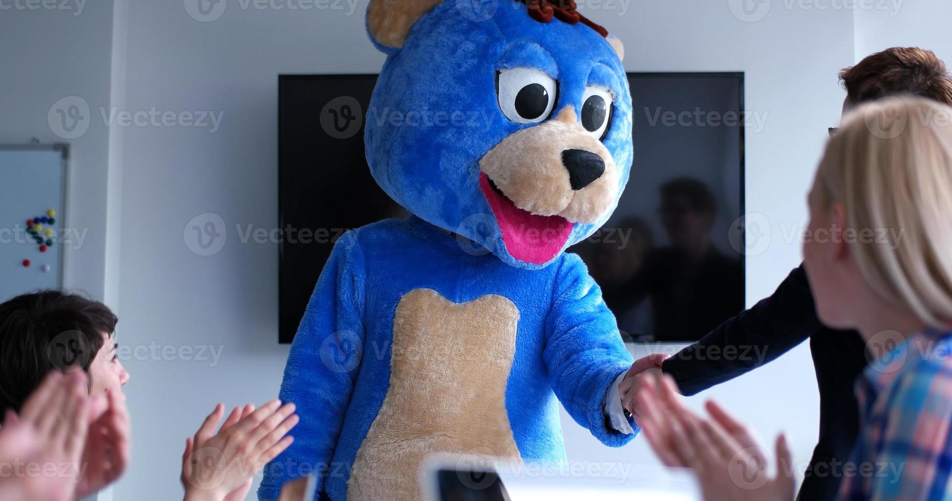 patron habillé en ours s'amusant avec des gens d'affaires dans un bureau branché photo